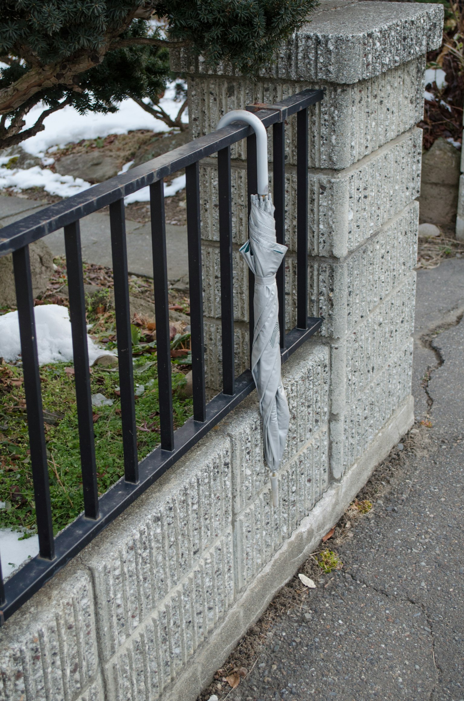 An umbrella hanging on a black metal fence