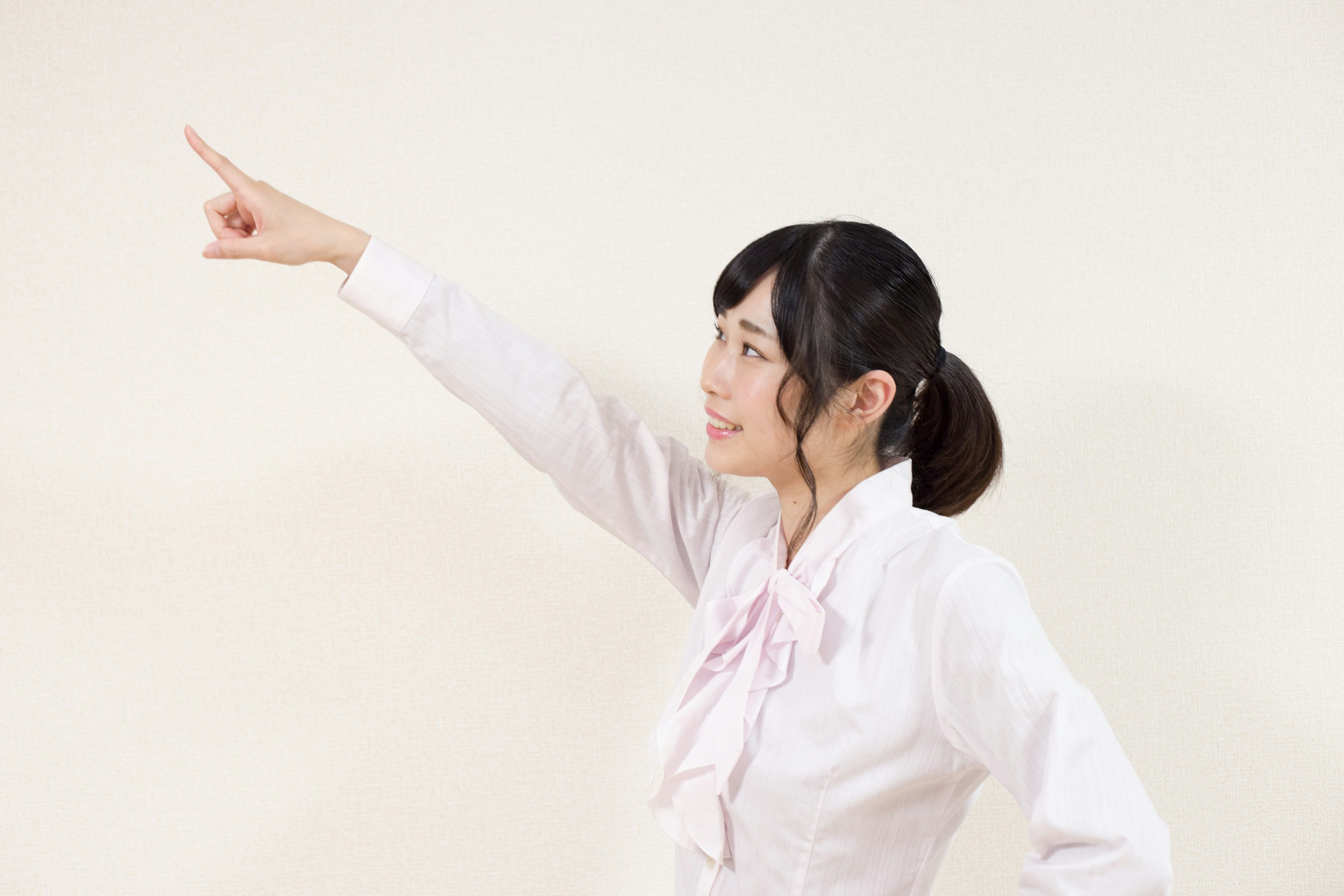 白い背景で指さす女性