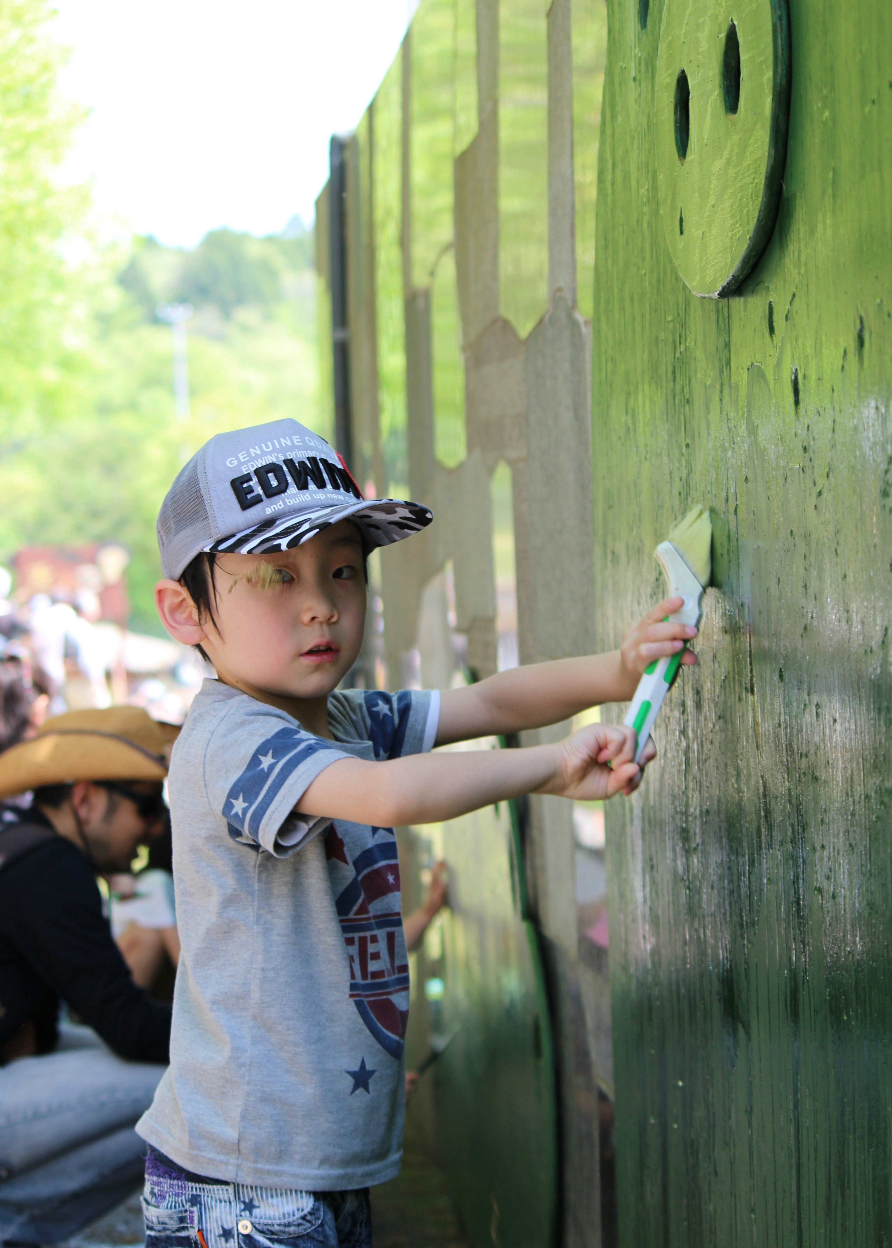 Child in a cap touching a wooden fence