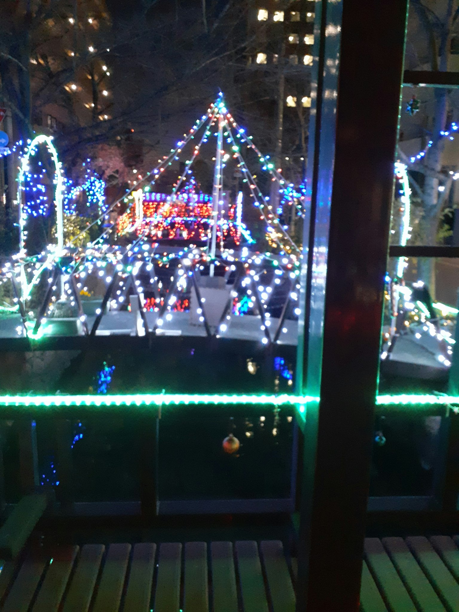 Scena notturna con luci colorate che illuminano un parco decorato in modo festivo