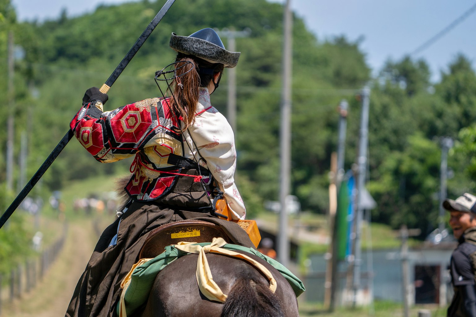 Une femme en tenue traditionnelle montant un cheval avec une lance à la main