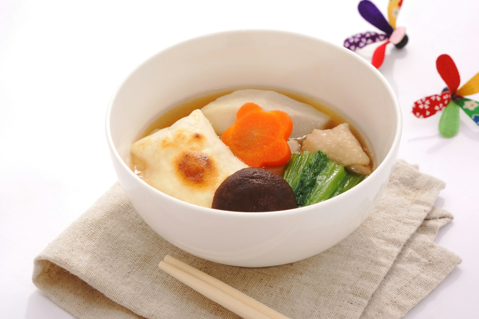 A white bowl filled with colorful vegetables and tofu soup