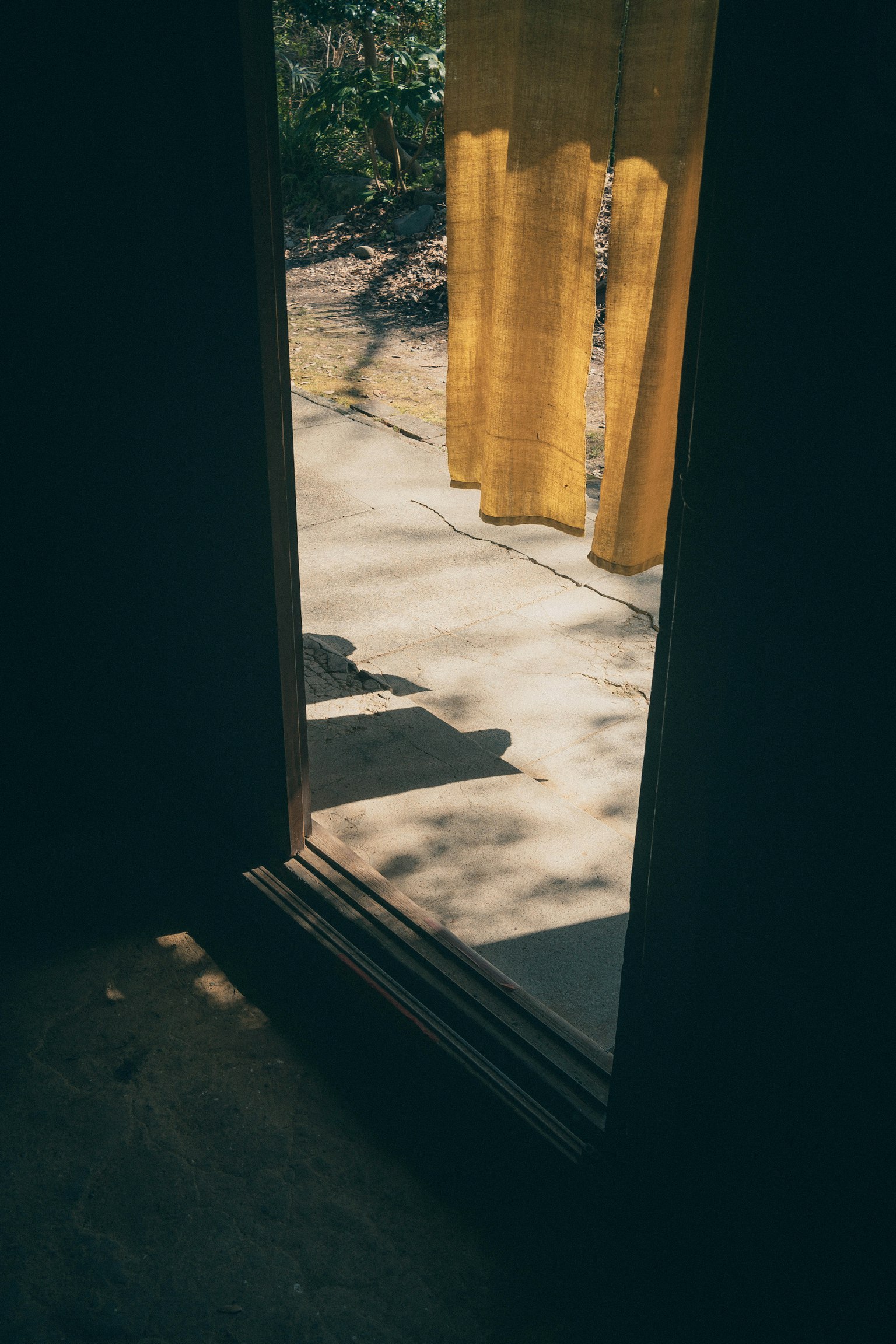 Vue à travers une porte ouverte montrant un rideau jaune et un paysage extérieur