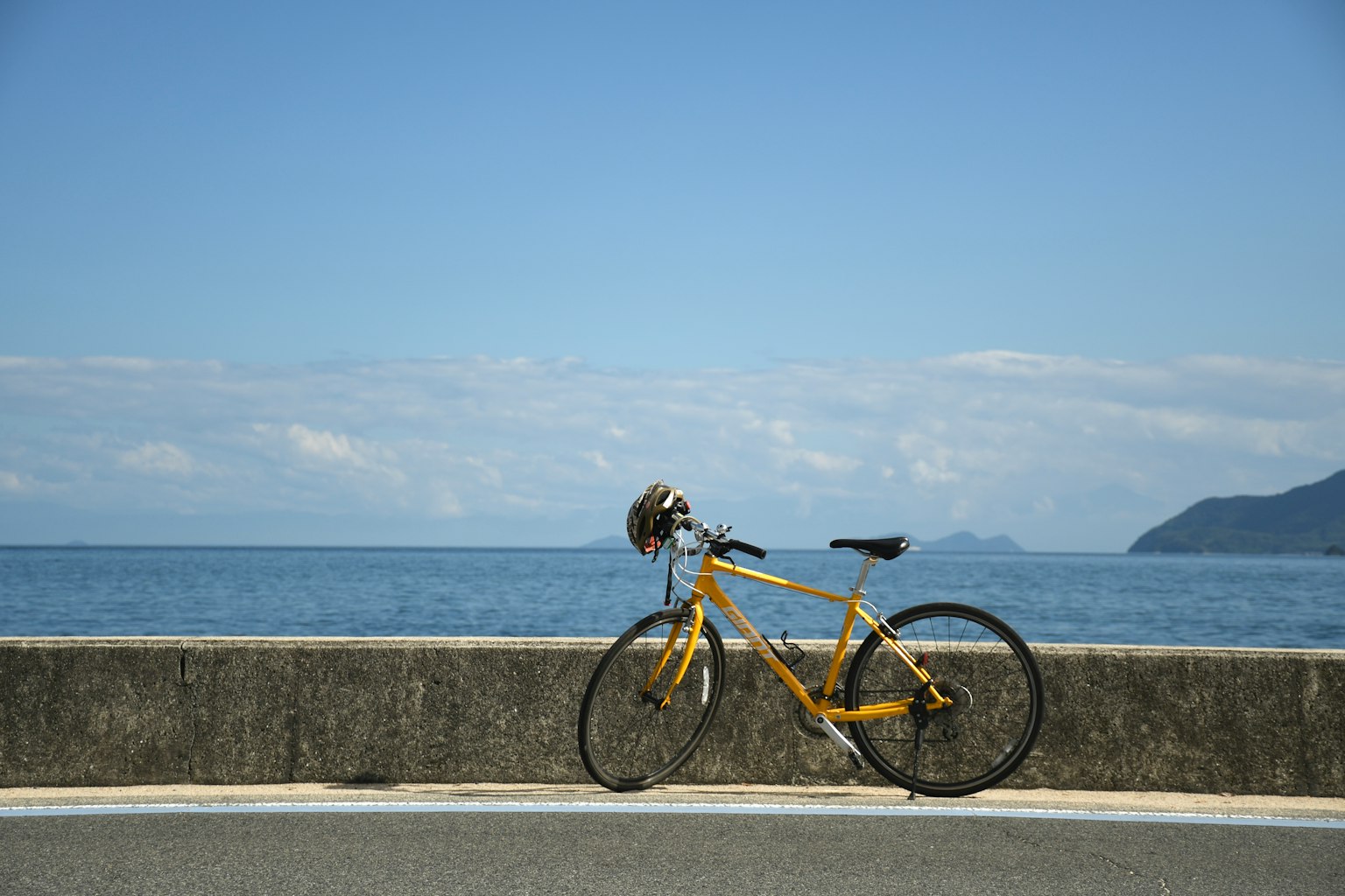 Una bicicletta gialla parcheggiata vicino all'oceano sotto un cielo blu chiaro