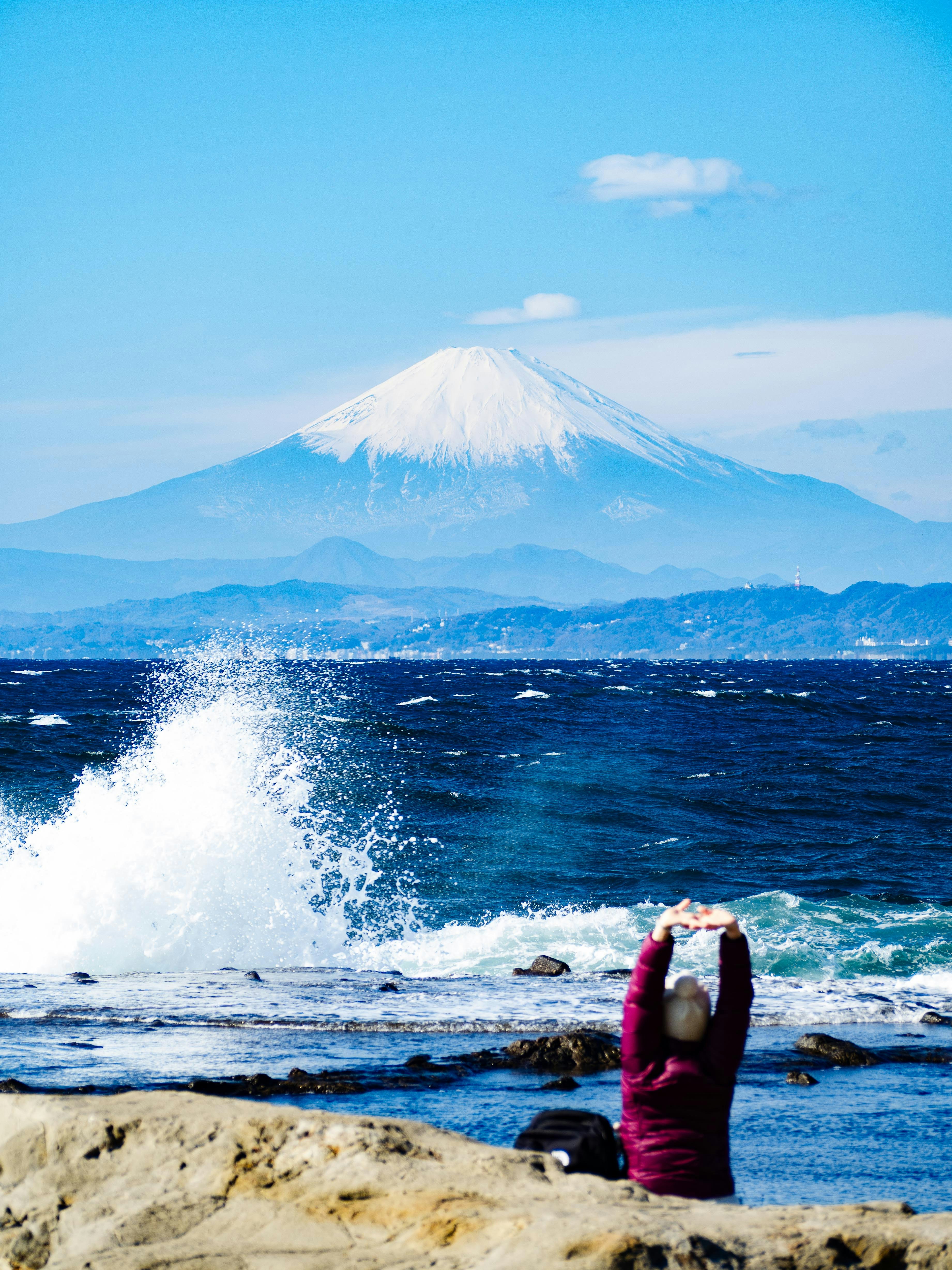 persona che si bagna sugli scogli con il Monte Fuji sullo sfondo