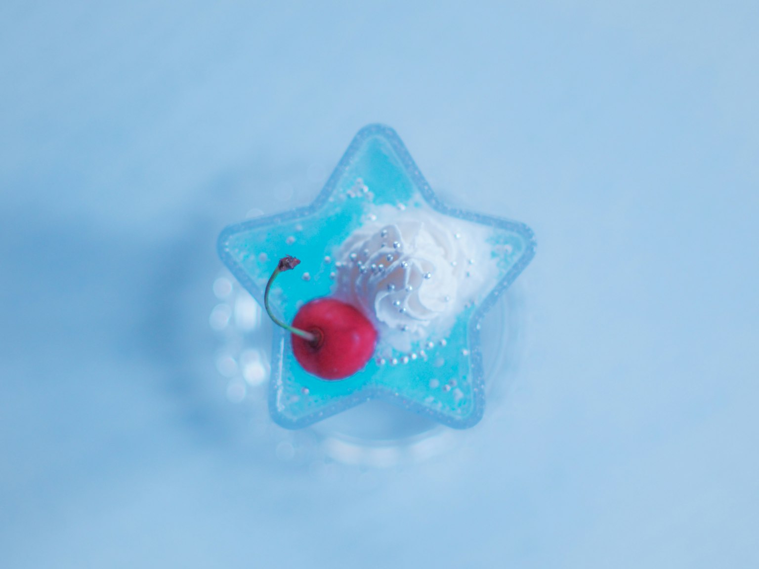 蓝色背景下星形容器内有椰子片和樱桃