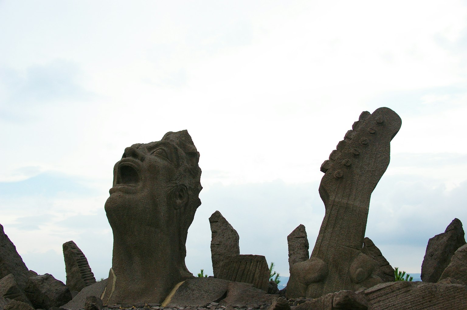 Scultura in pietra di un volto umano e piedi che guardano il cielo