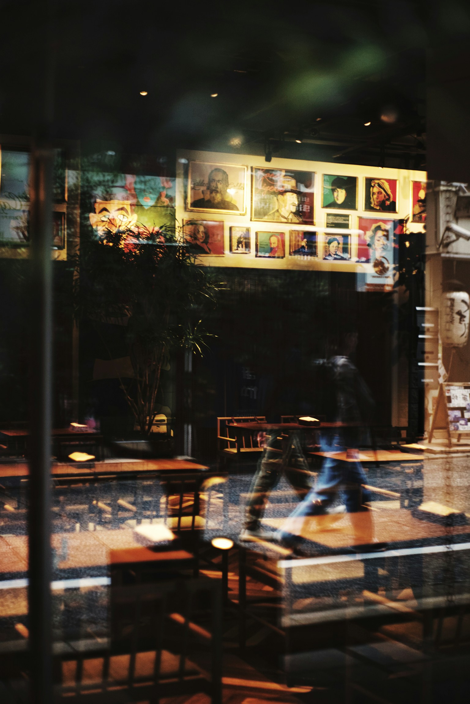 Interior of a dimly lit café with tables and chairs Artworks displayed on the wall