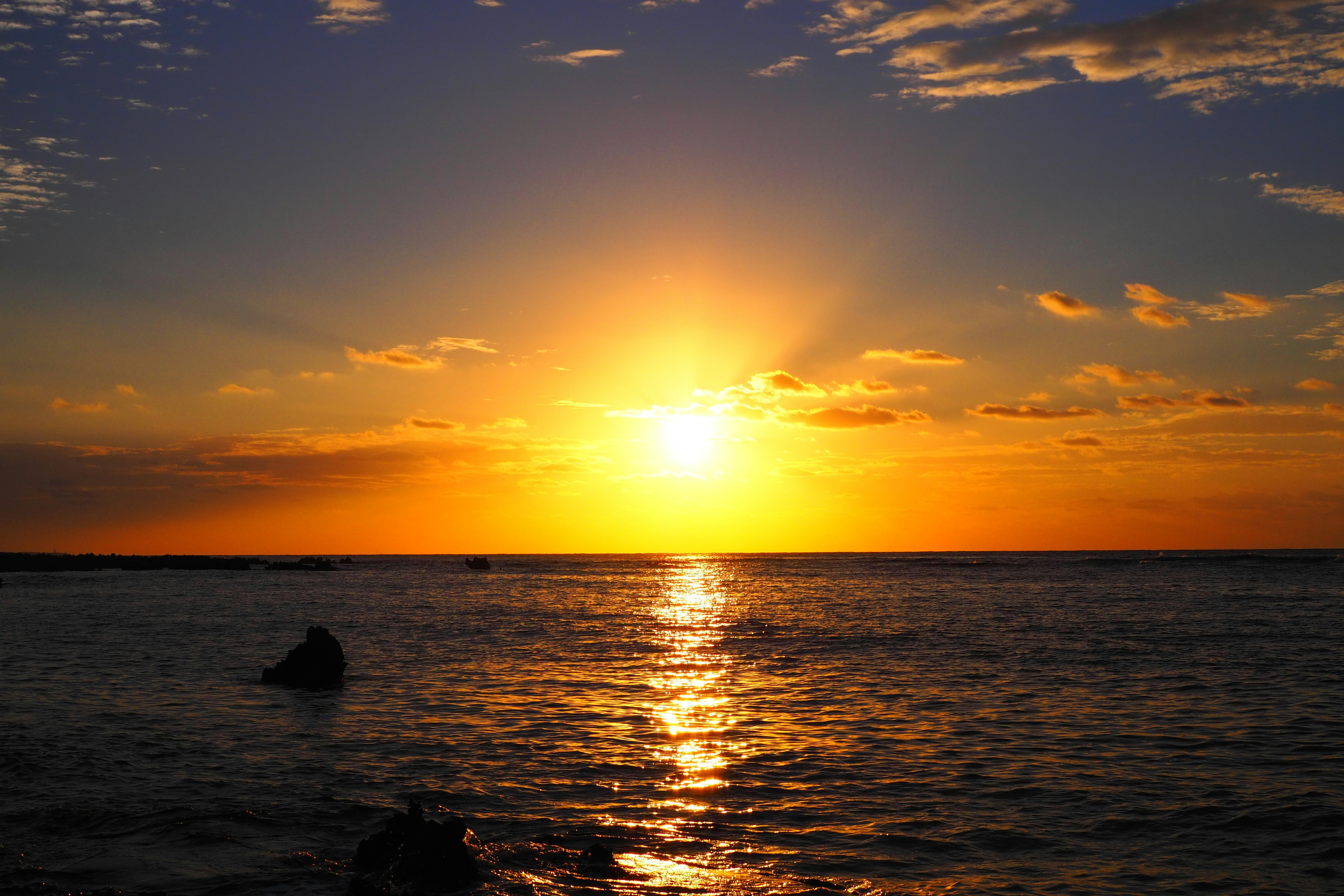 水平線に沈む夕日と波のある海の風景