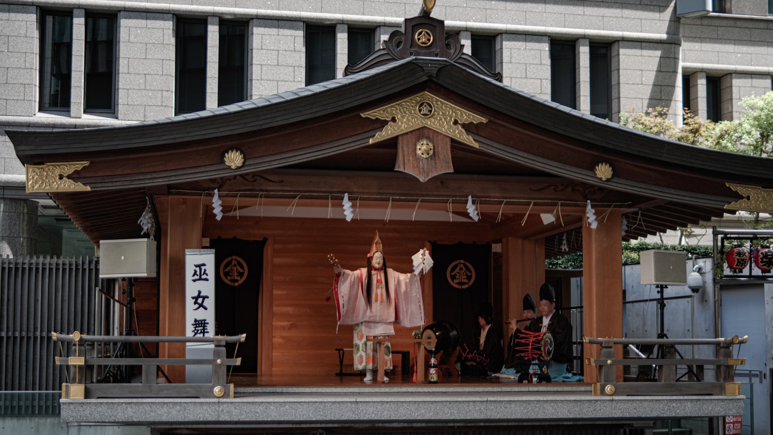 Eine traditionelle japanische Schreinanlage mit einem Priester, der eine Zeremonie auf einer Freiluftbühne durchführt