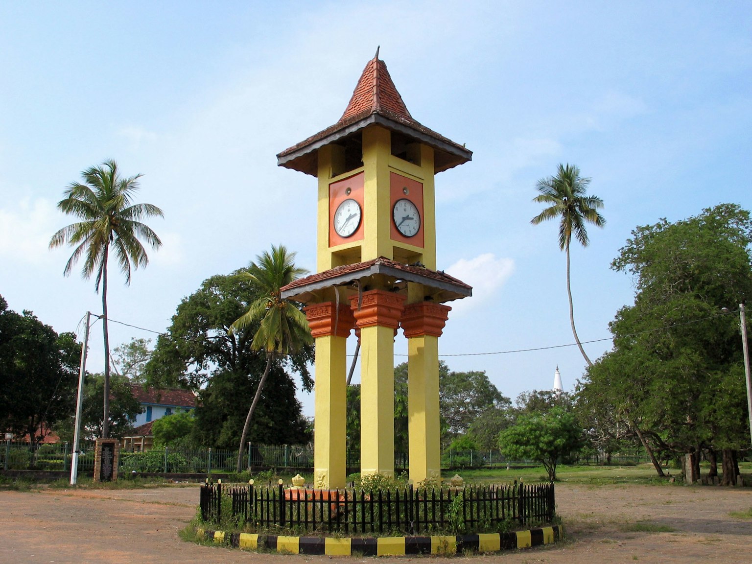 Menara jam kuning dikelilingi oleh pepohonan