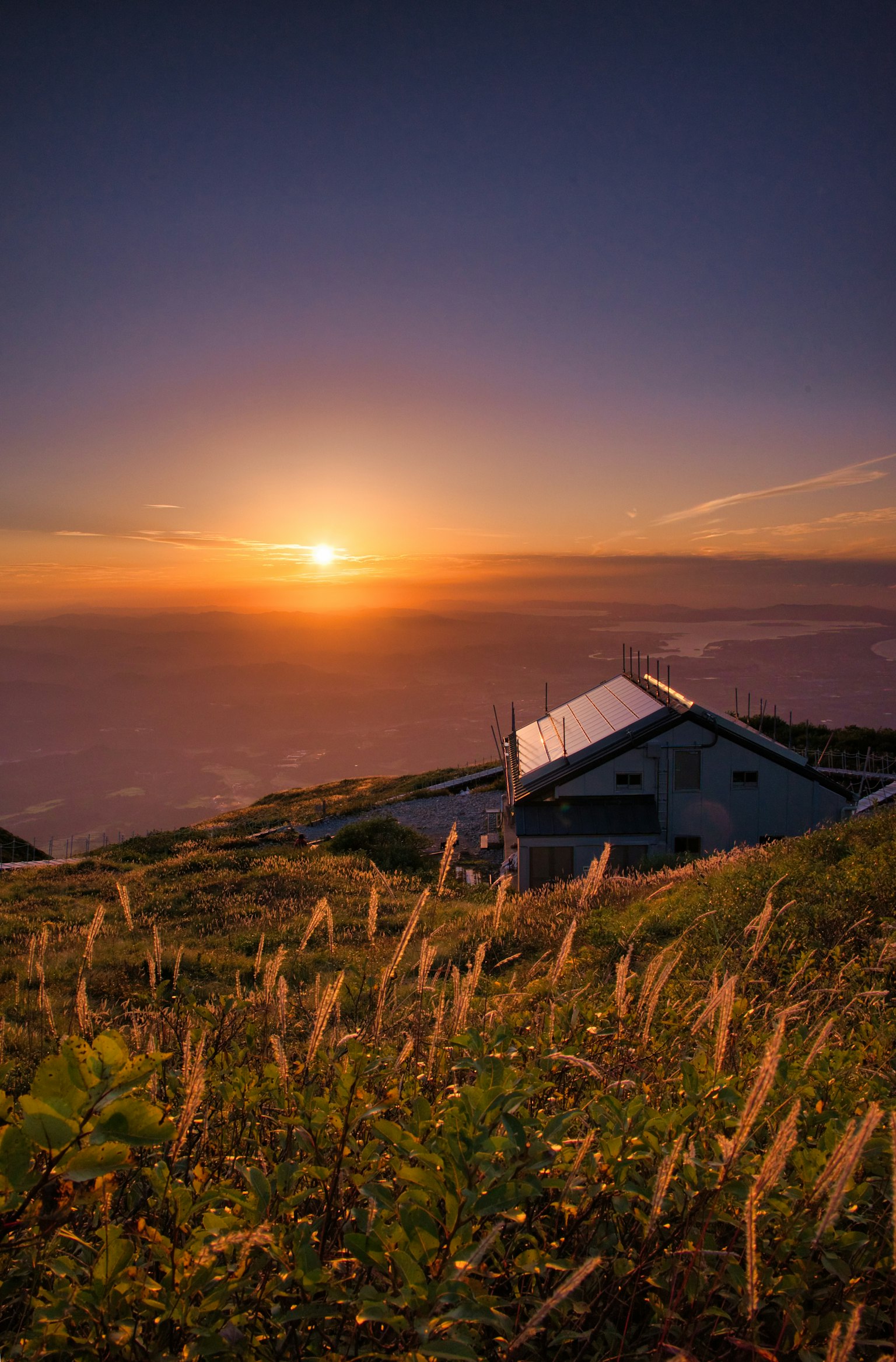 夕日が沈む美しい風景と草原の中にある家