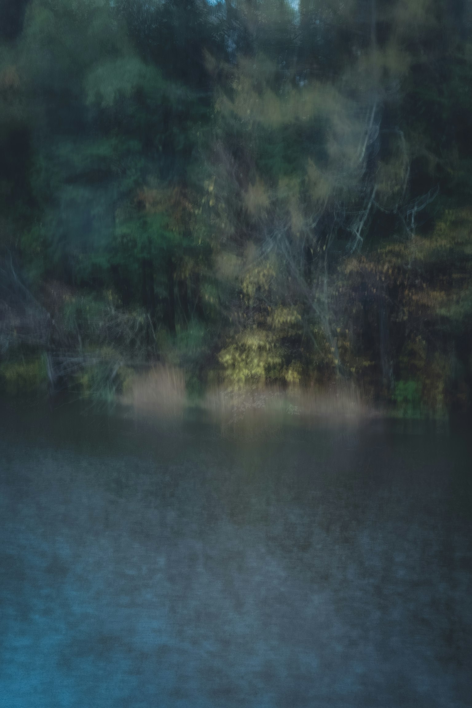 Verschwommene Wasseroberfläche, die Bäume im Hintergrund spiegelt
