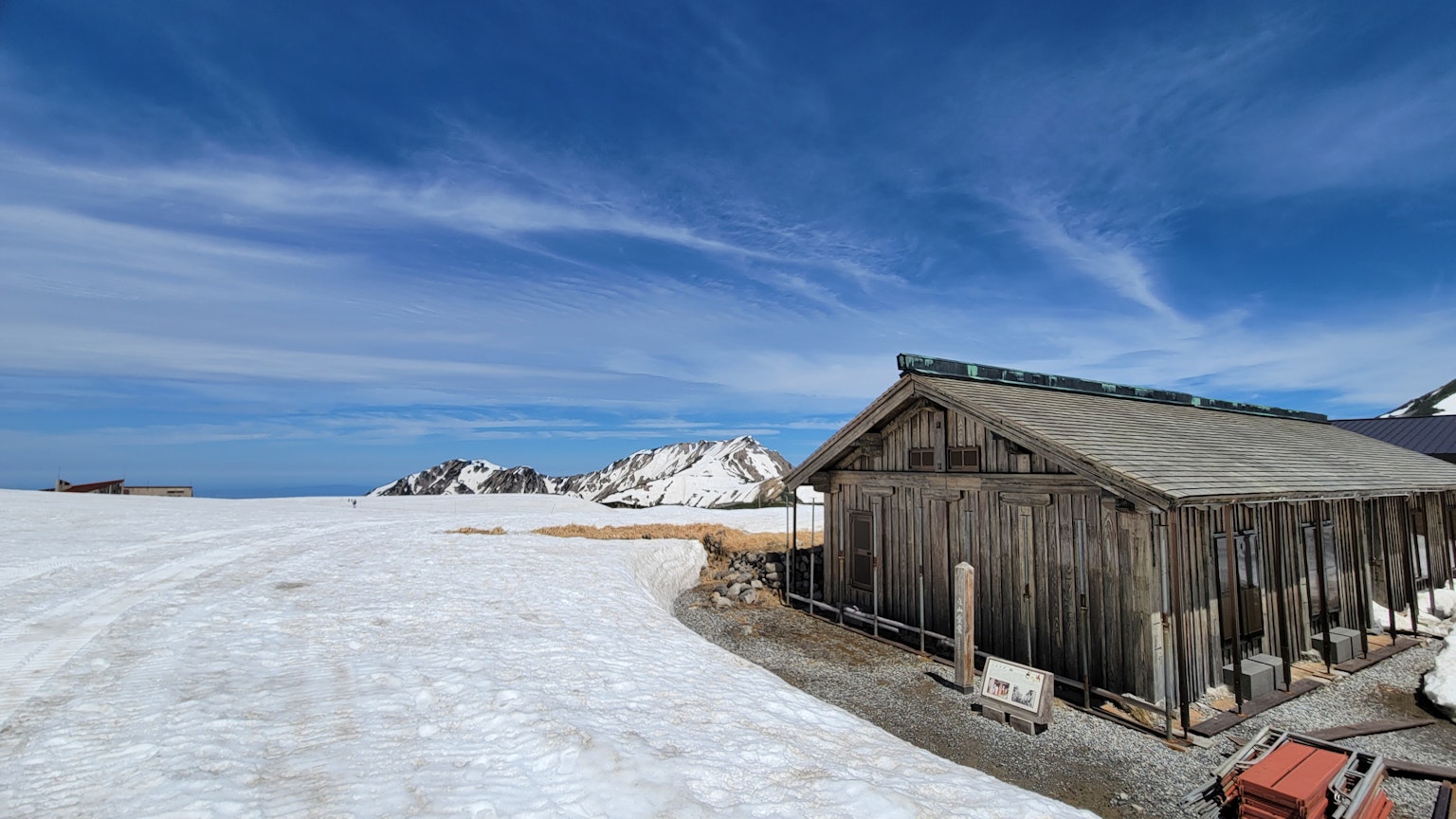 Wooden cabin on a snowy landscape under a blue sky