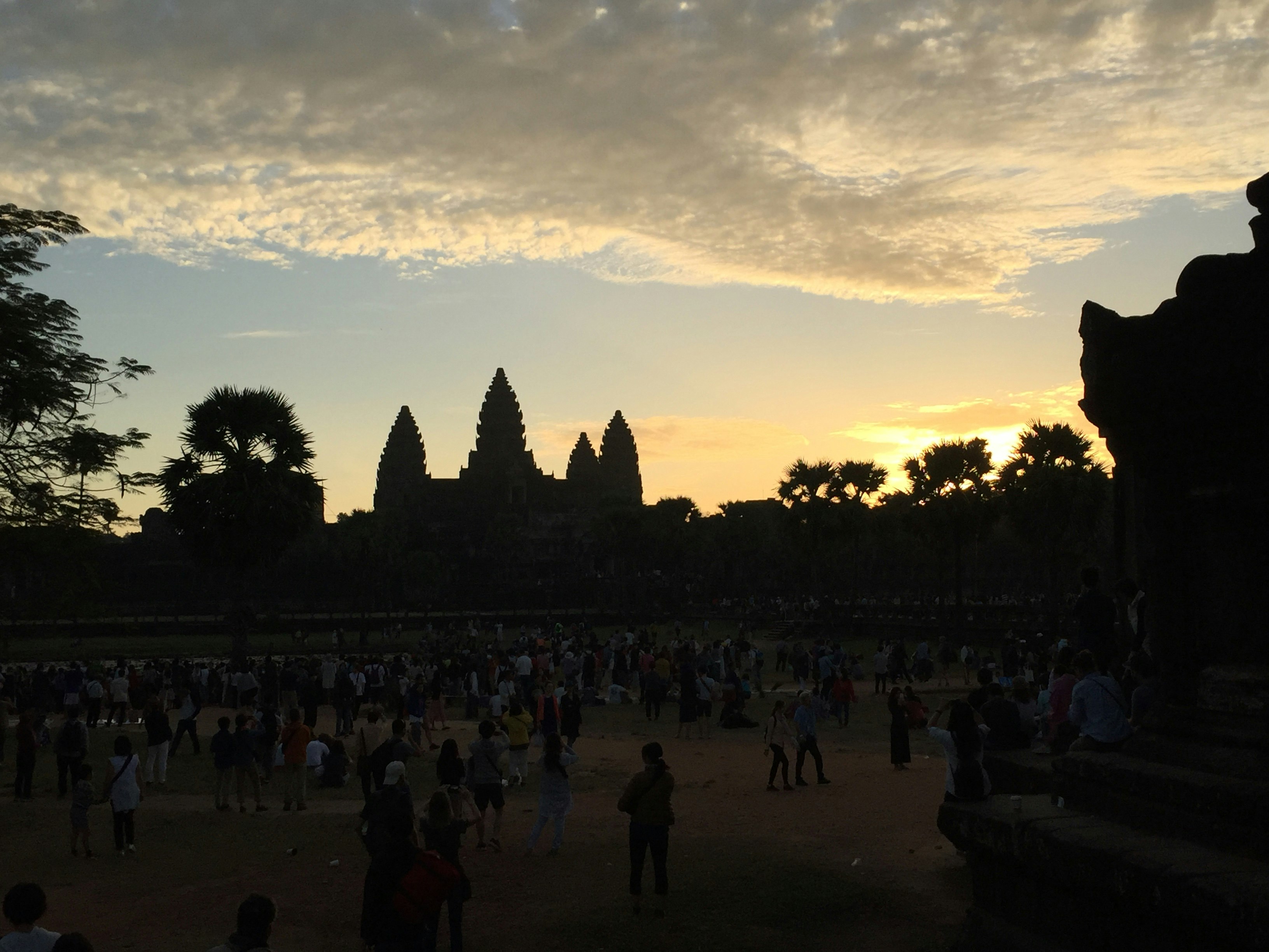 personnes rassemblées sur une place avec des silhouettes de temples anciens au coucher du soleil