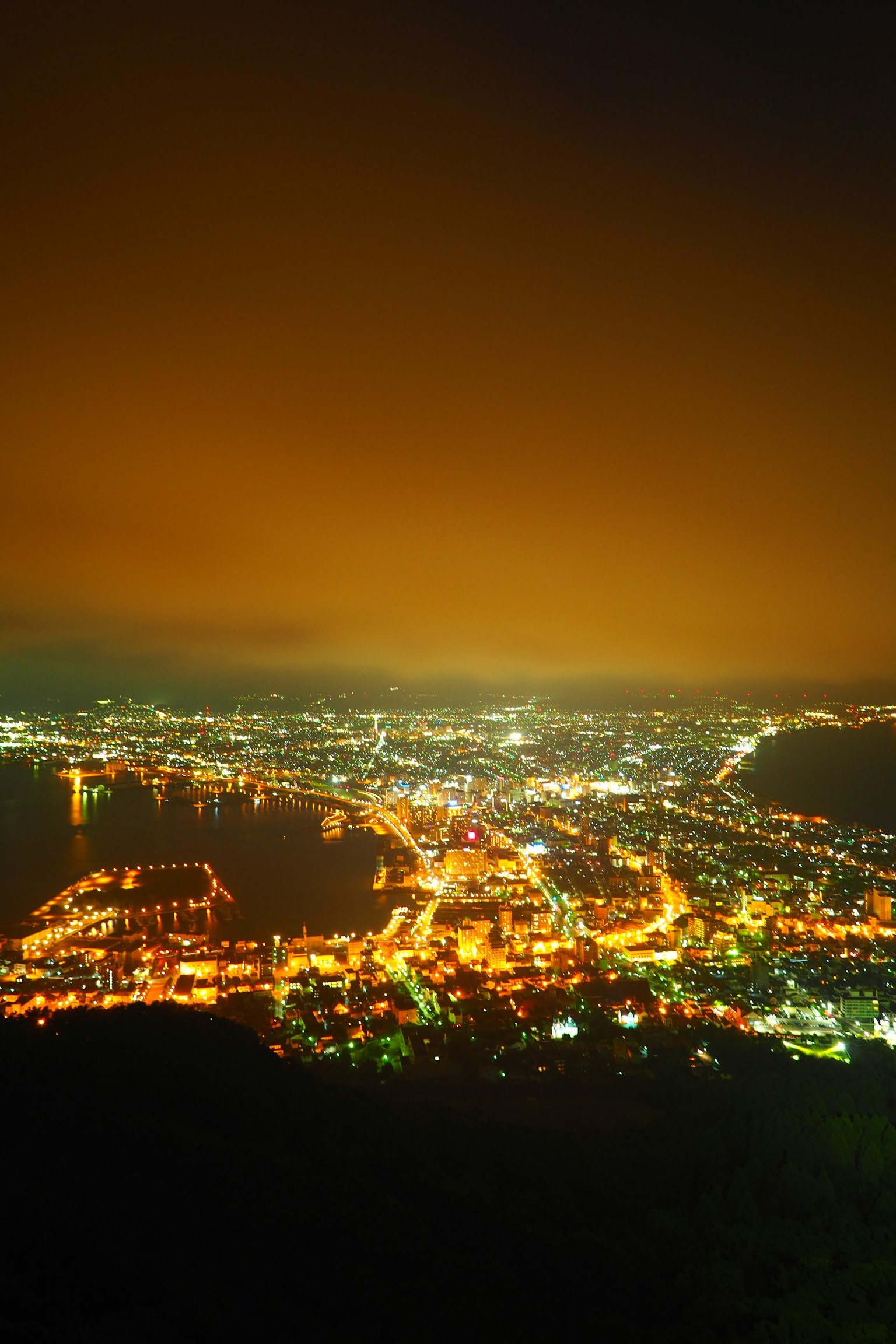Vue nocturne d'une ville avec des lumières brillantes et un horizon lumineux