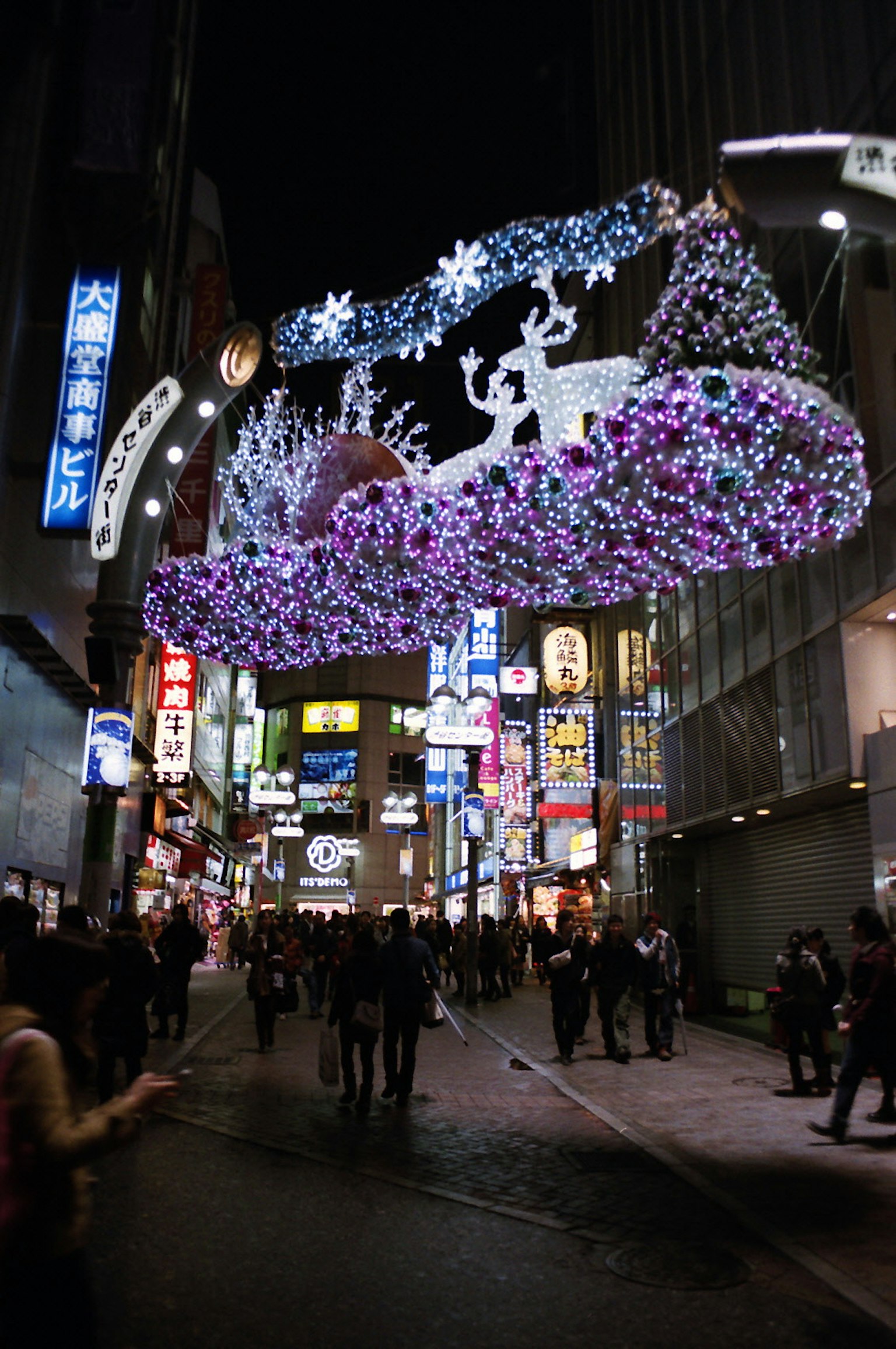 夜晚装饰城市街道的生动圣诞灯光与行人