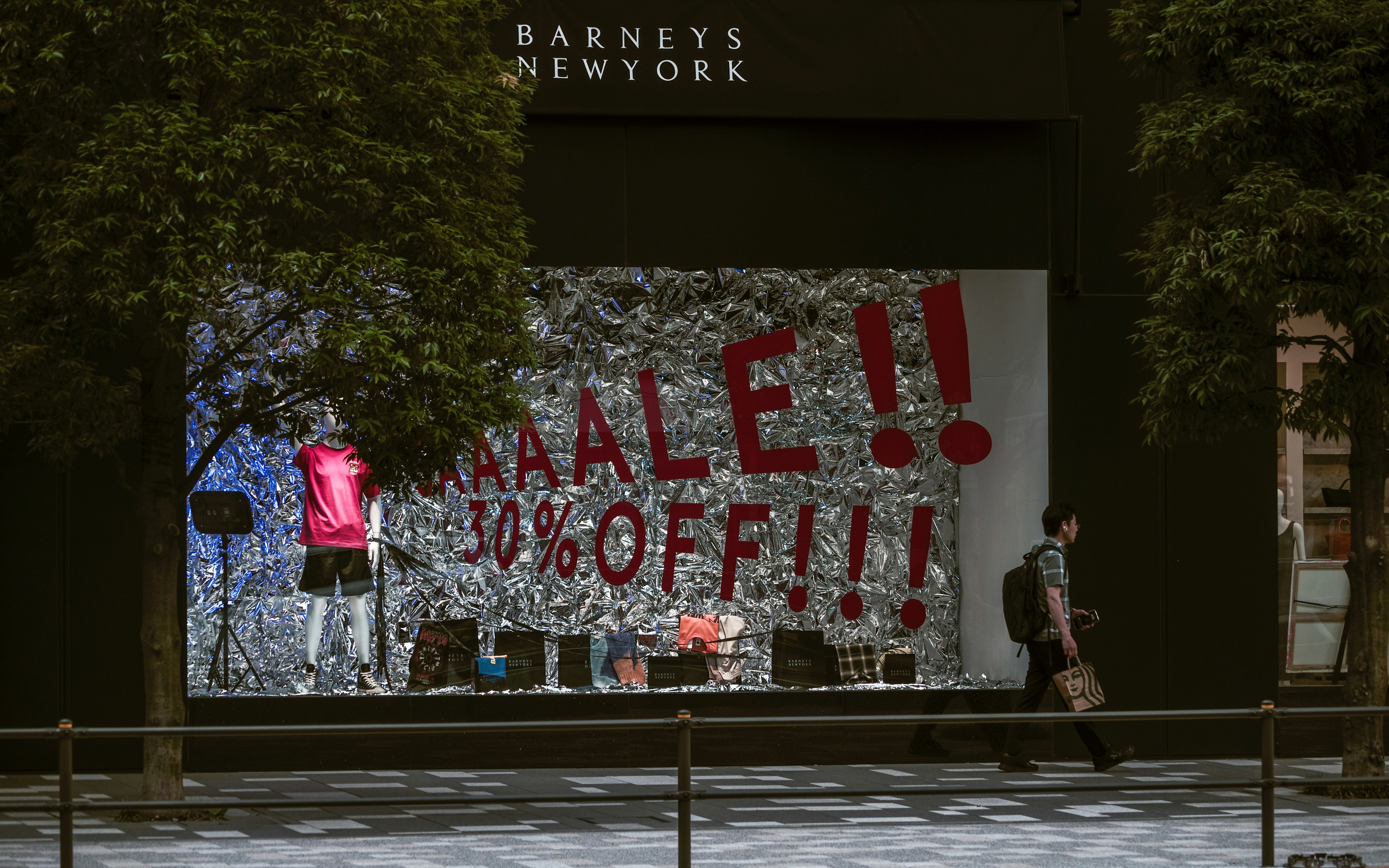 「SALE」看板の前を歩く人々のある街頭風景