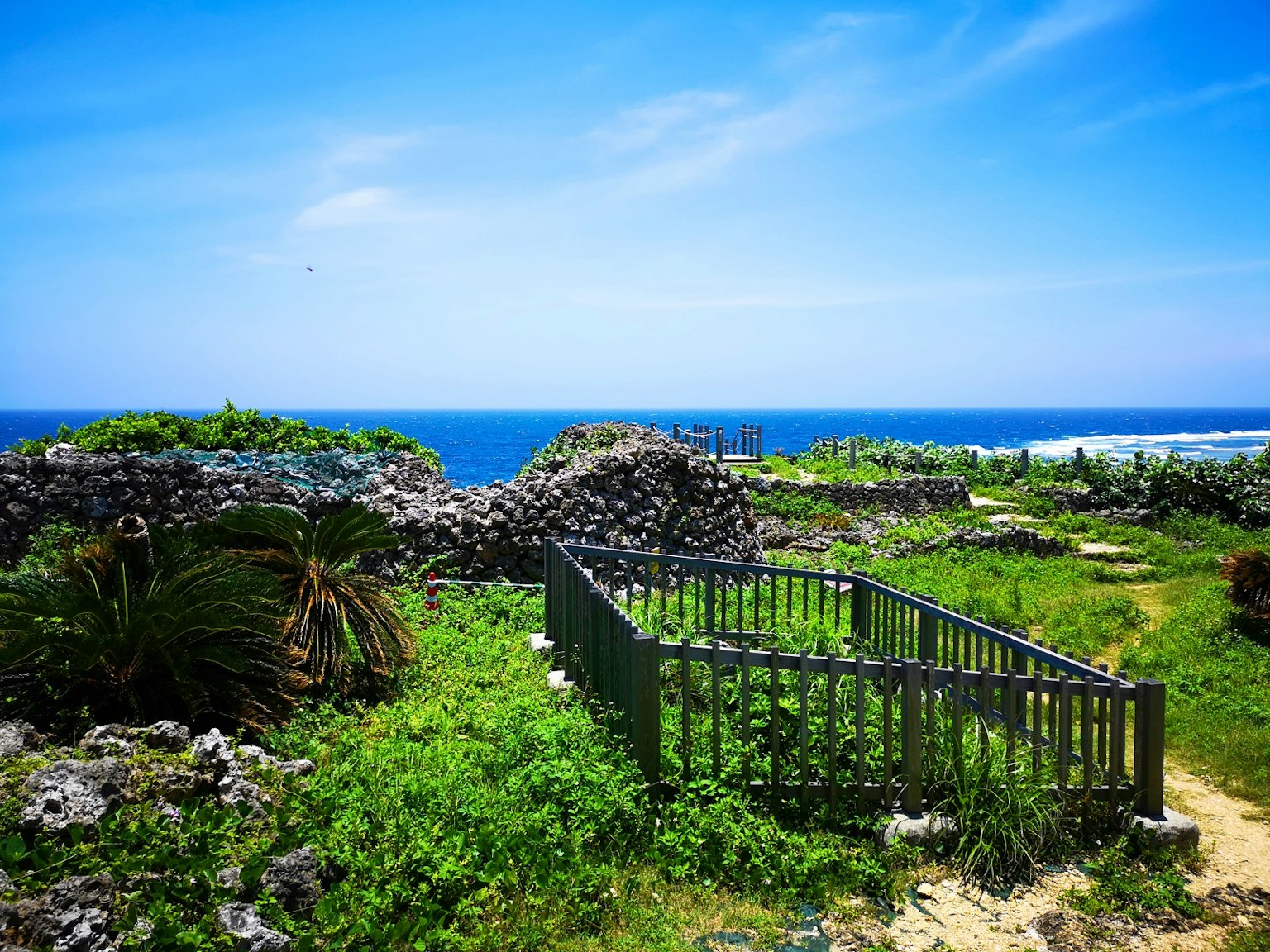 Vista panoramica delle rovine circondate da vegetazione e oceano blu