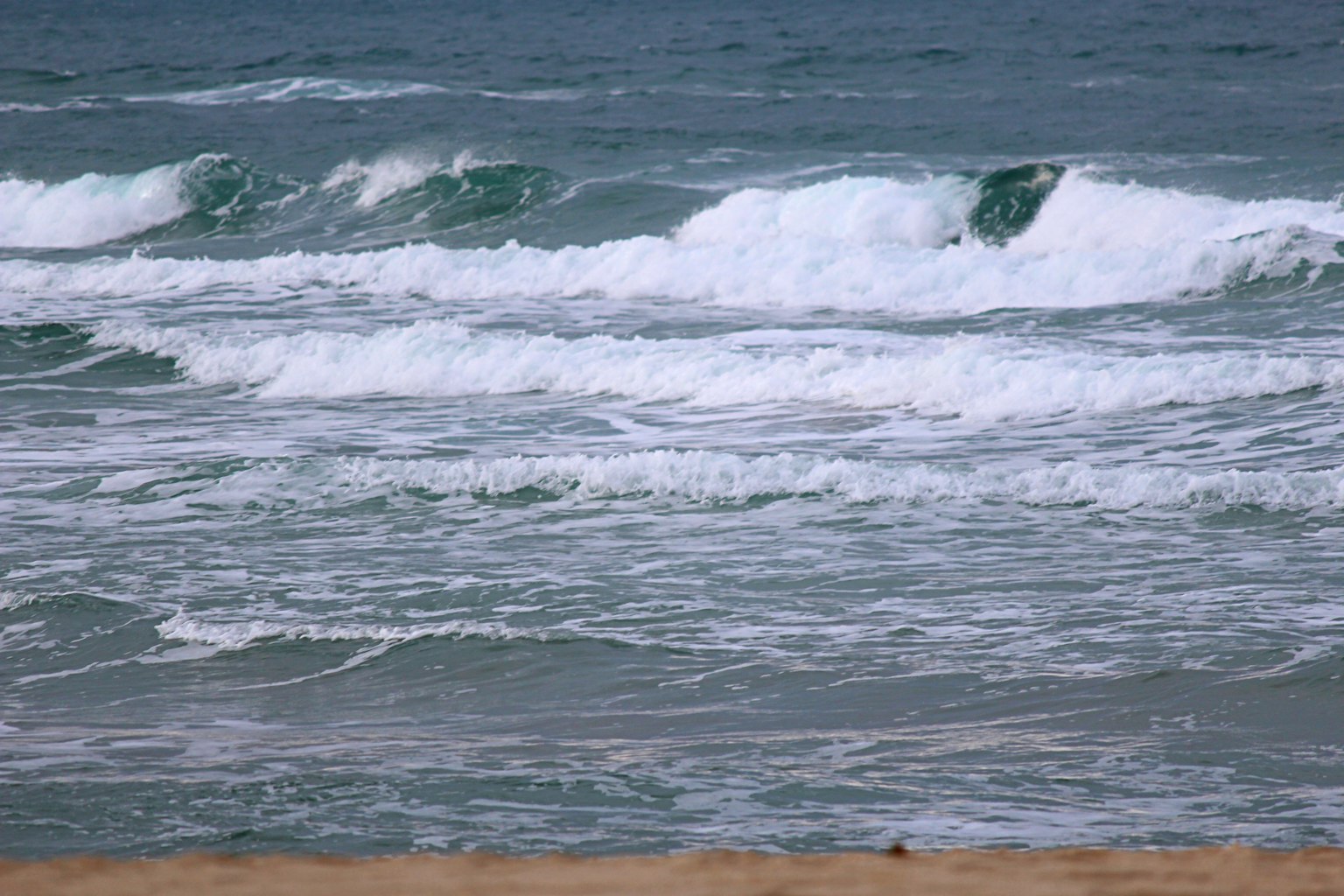 Vista costera con olas rompiendo y playa de arena