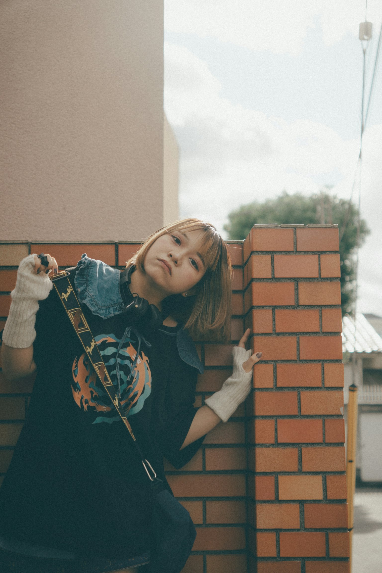 Woman leaning against a brick wall wearing casual attire