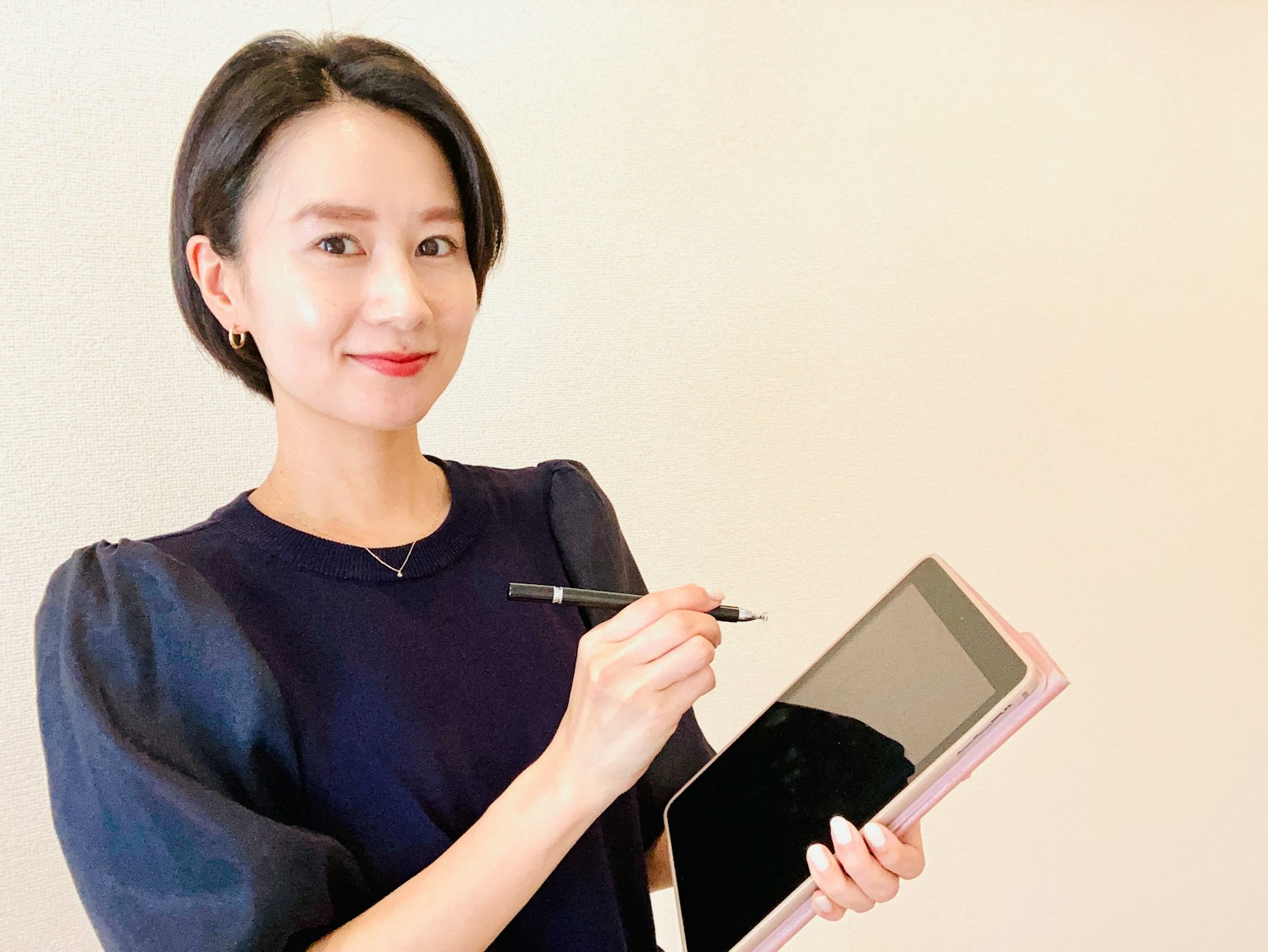 Seorang wanita memegang tablet dan menulis dengan pena