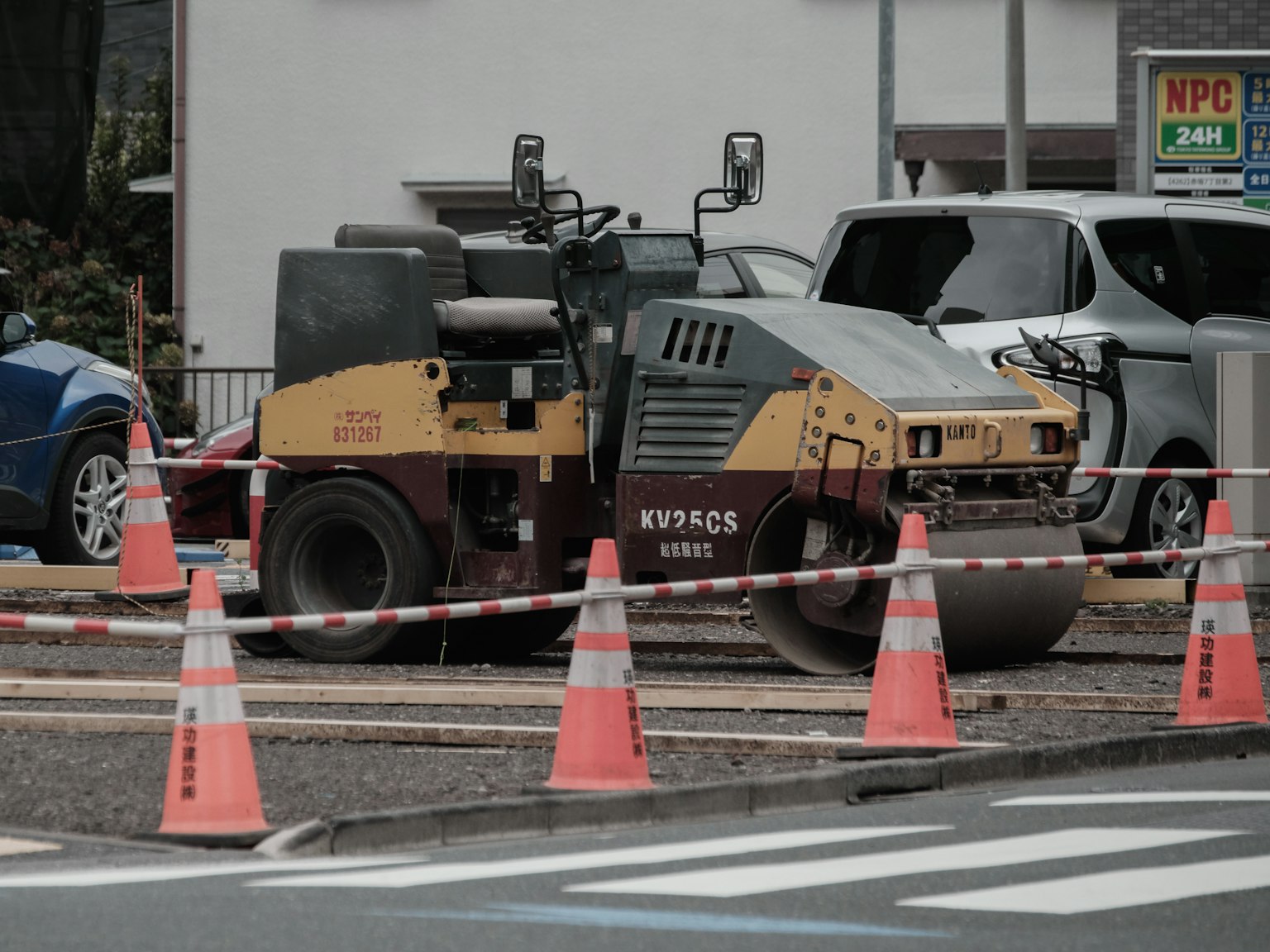 Site de construction avec un rouleau compresseur et des cônes orange dans un parking