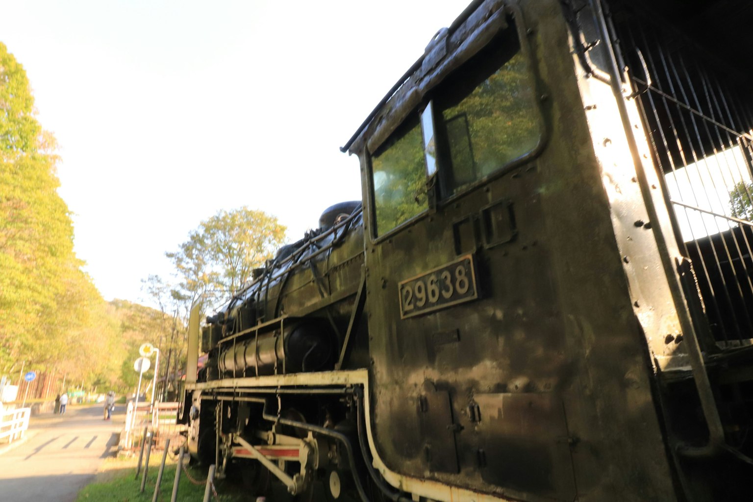 Seitenansicht einer alten Dampflokomotive mit grünen Bäumen im Hintergrund