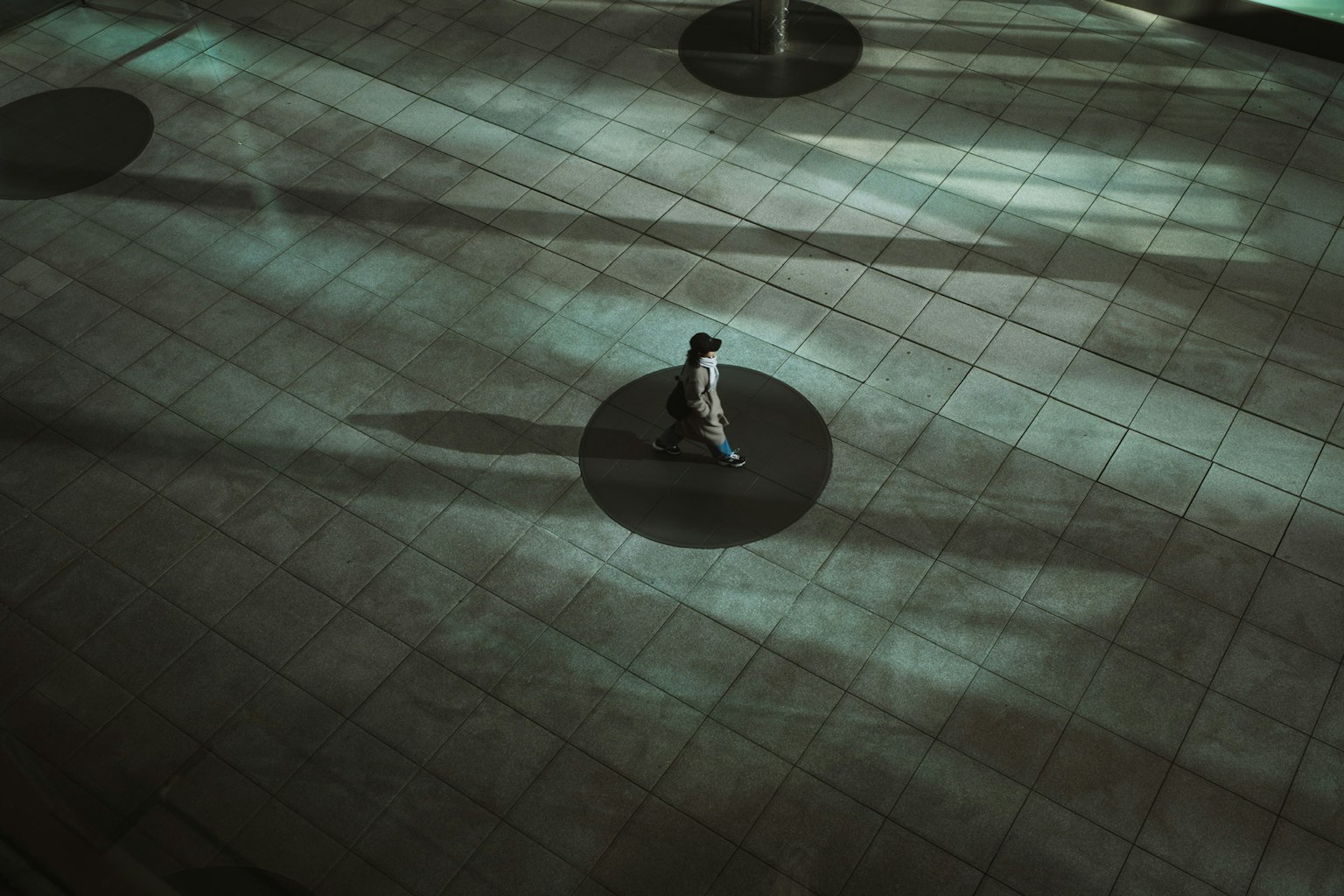 Silhouette di una persona che cammina su un pavimento con ombre