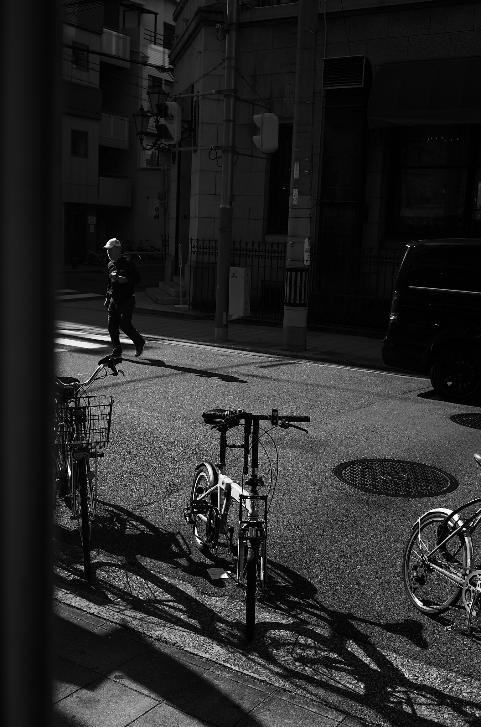 白黒の街角に自転車が並び、通行人が歩いているシーン