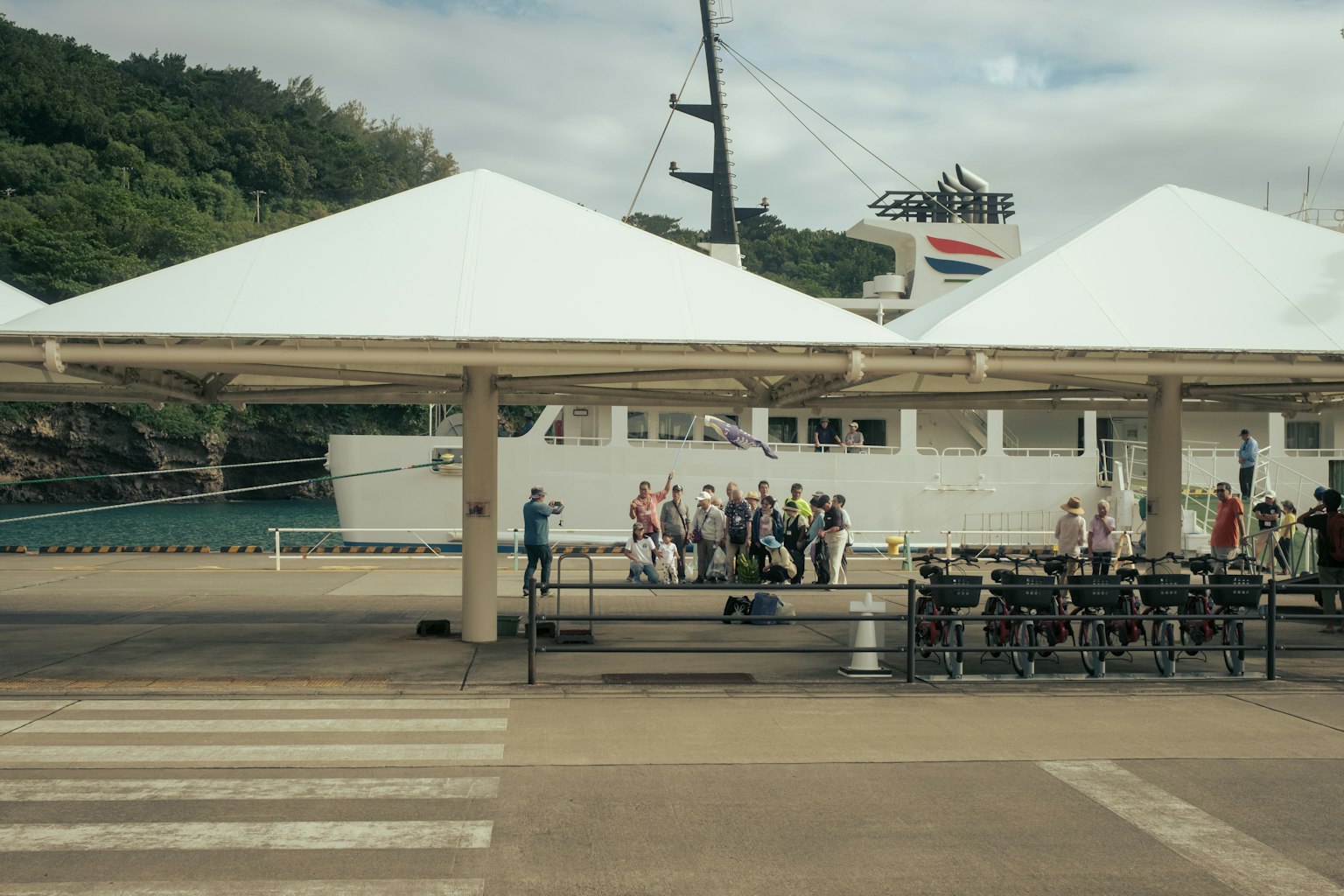 人們在白色帳篷下聚集，背景是港口和船隻