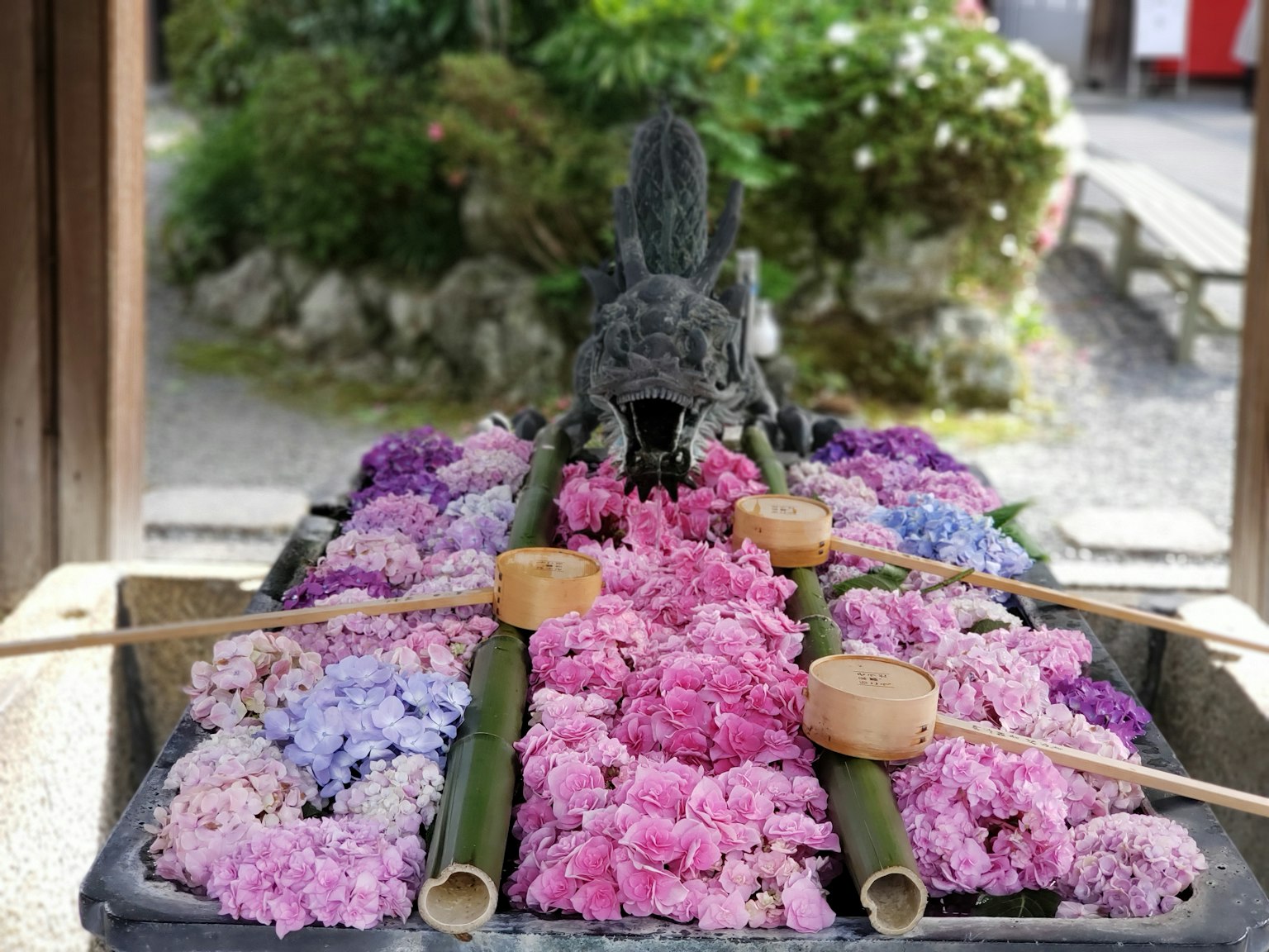 Un estanque de piedra decorado con flores coloridas y un pico de dragón para el agua