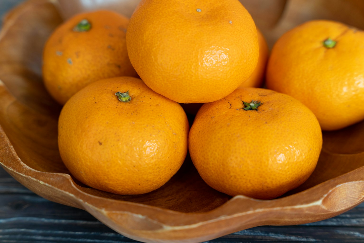 Lima jeruk mandarin oranye dalam mangkuk kayu