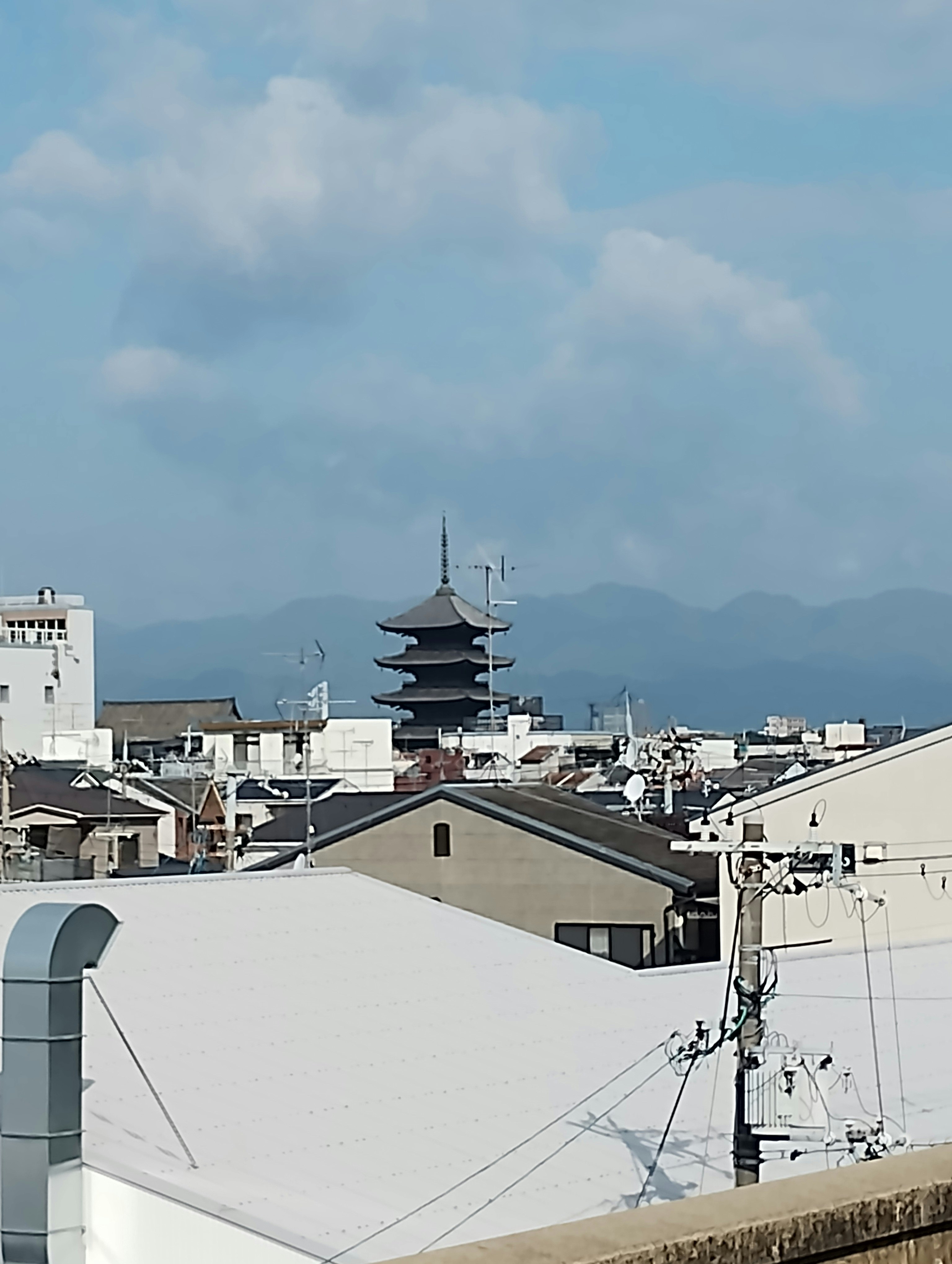 Rooftops overlooking the sea, sky, distant mountains, and a pagoda
