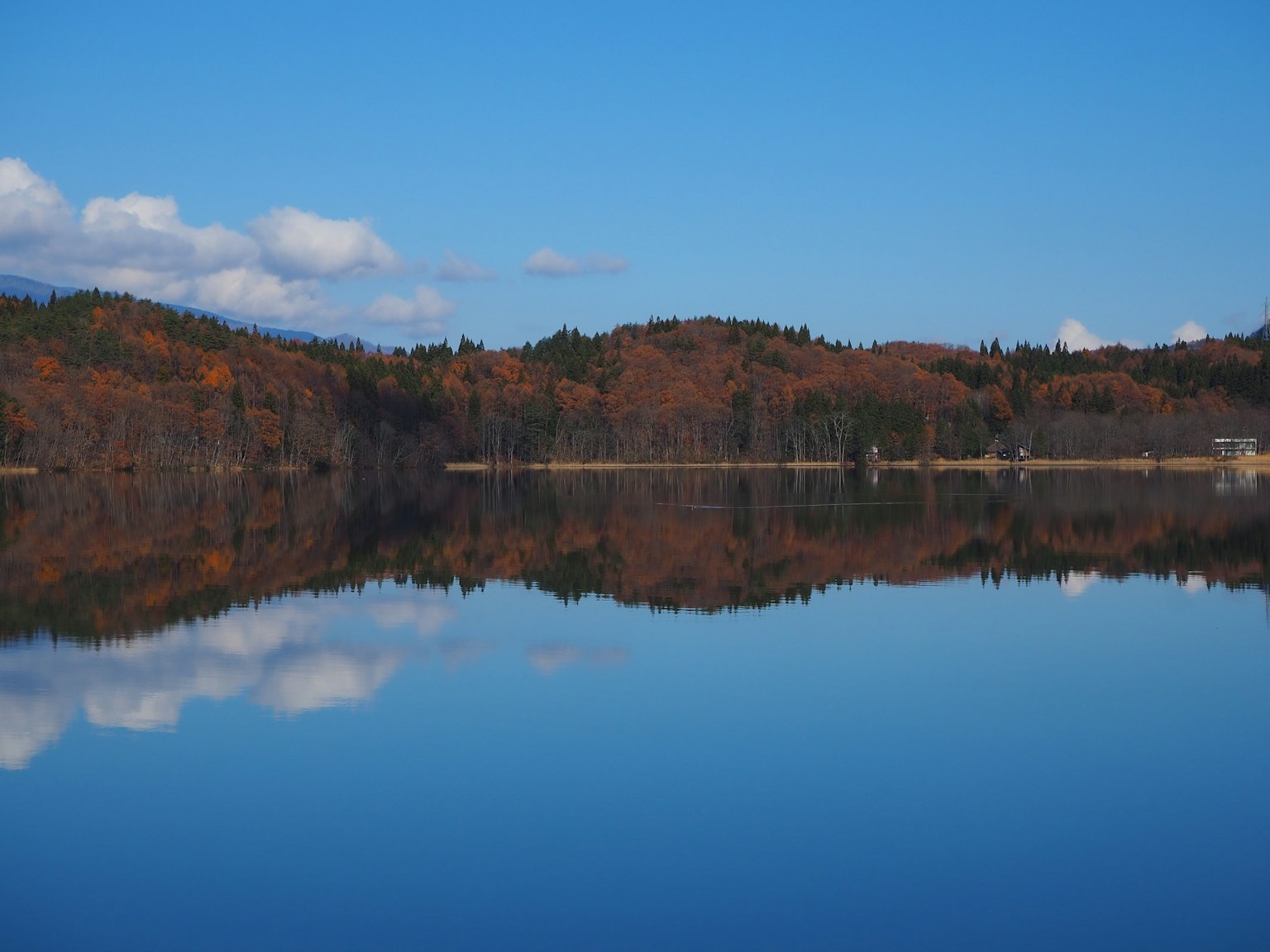 Lac calme reflétant le ciel bleu et le feuillage d'automne