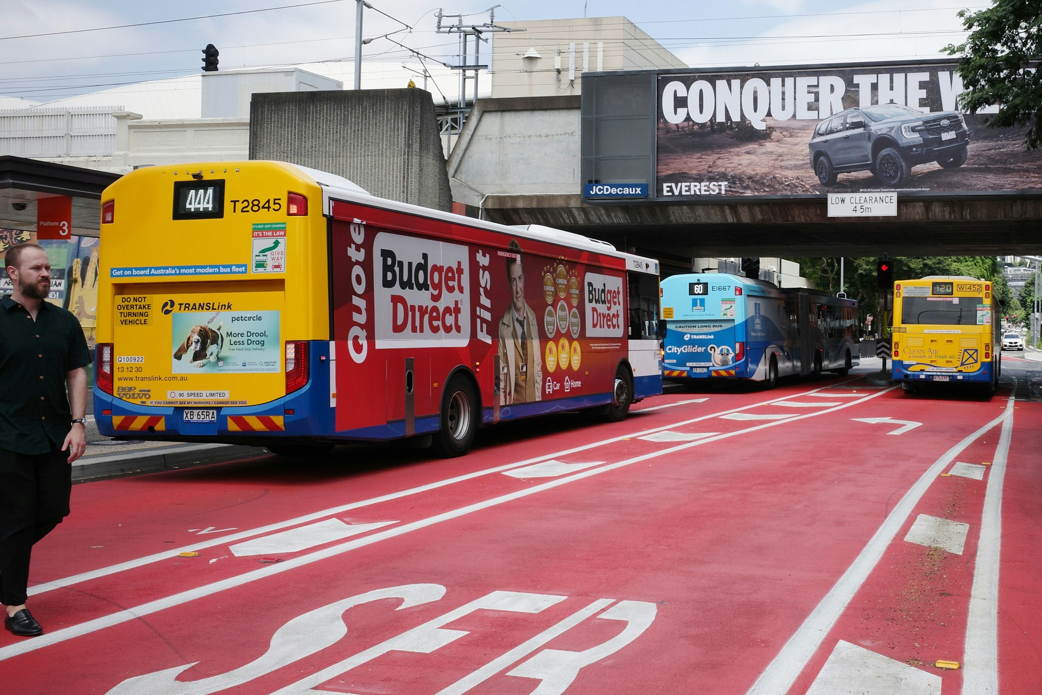 赤いバス専用レーンを走るバスと広告看板が見える都市の風景