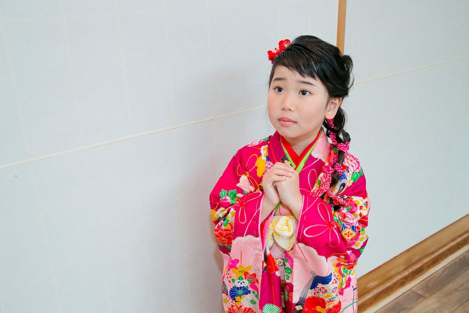 Seorang gadis muda mengenakan kimono merah muda cerah dengan pola bunga berdiri anggun
