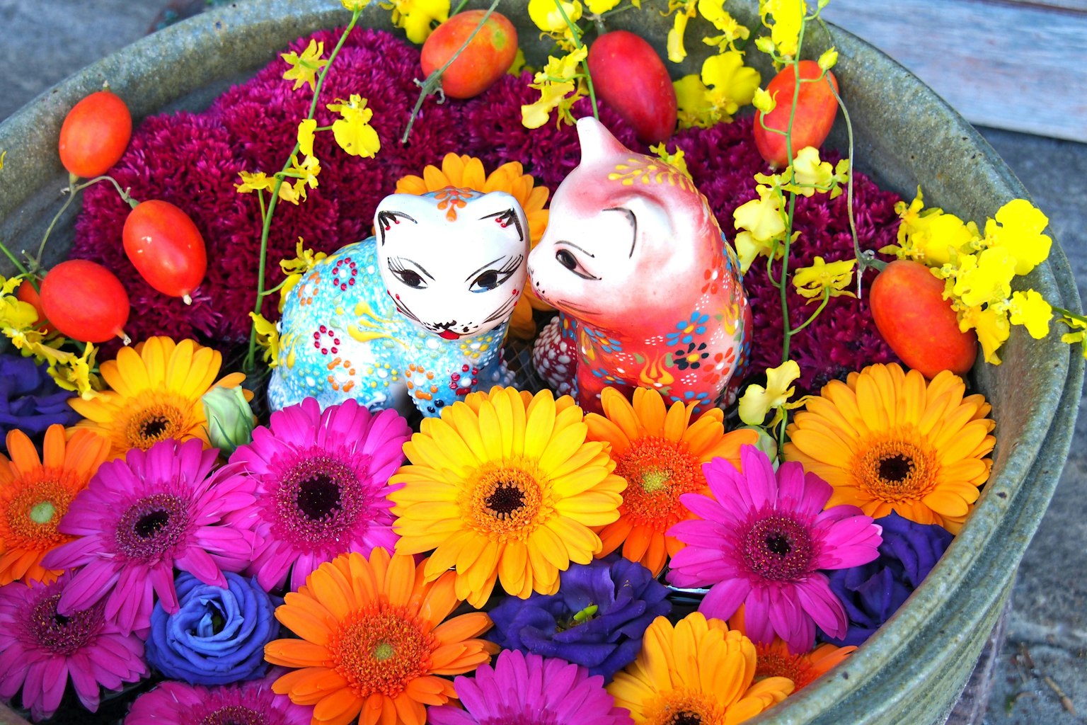 Fiori colorati e figurine di gatti in ceramica in una ciotola