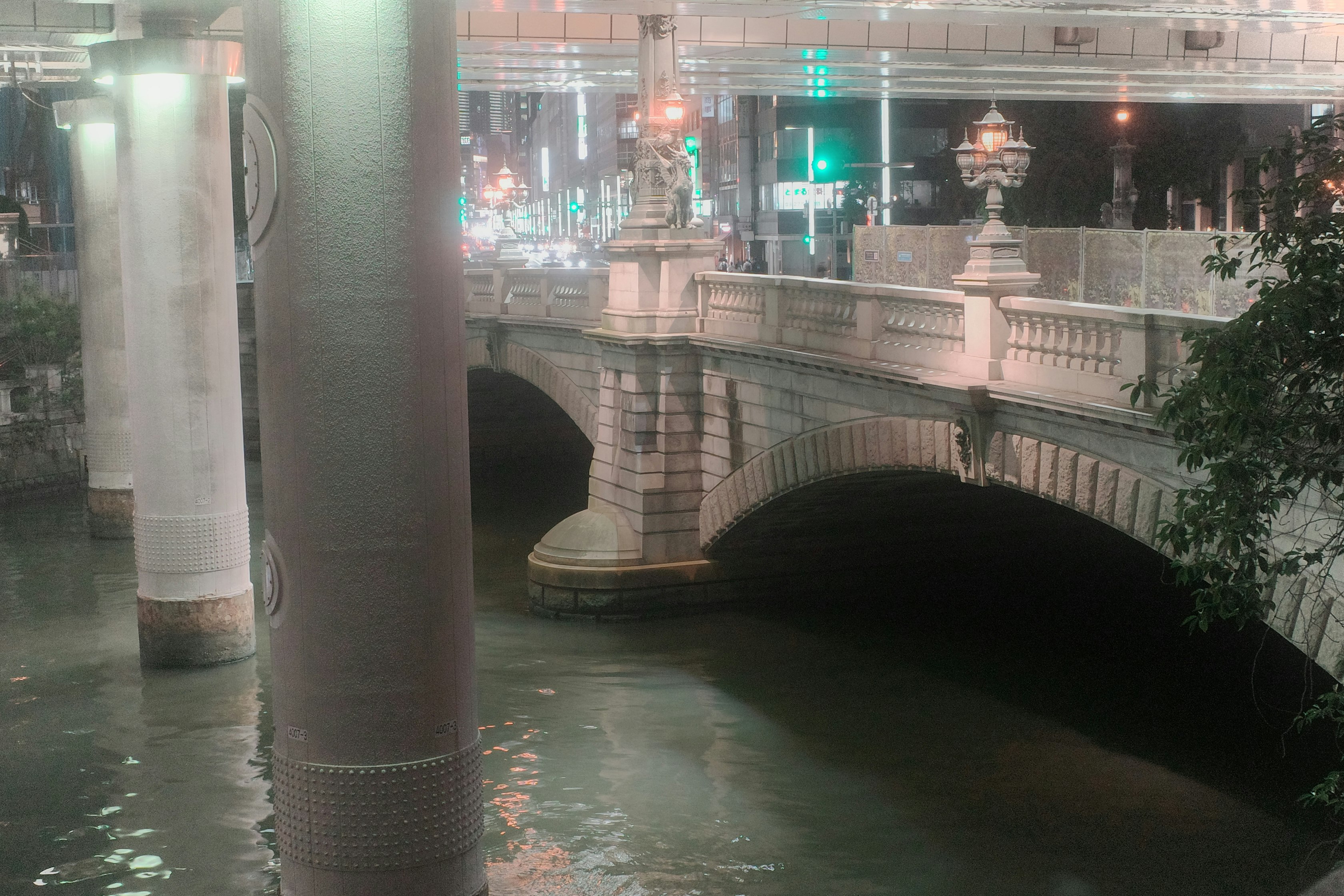 水辺のアーチ橋と街の夜景が見える屋内通路