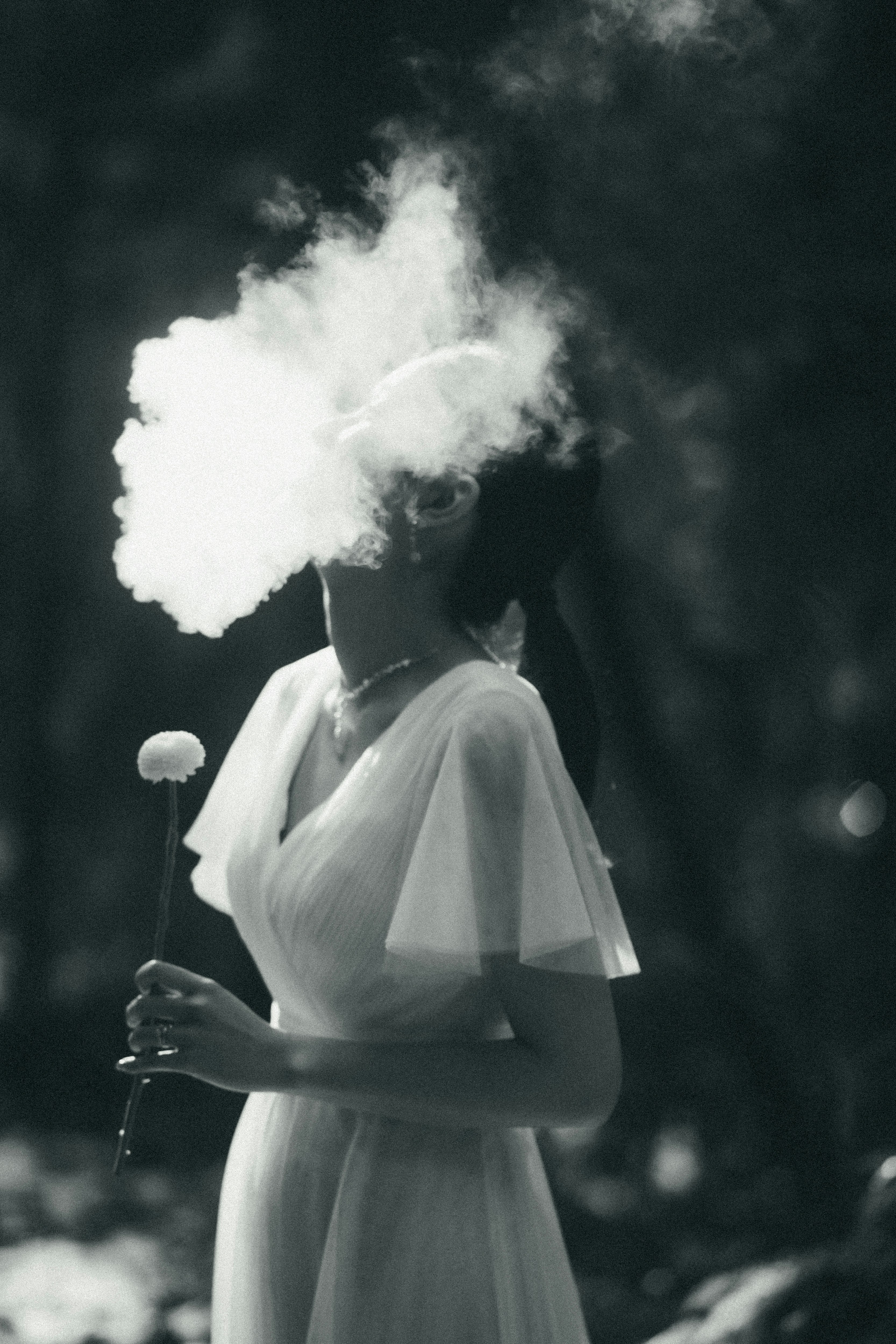 Une personne en robe blanche tendant la main dans une brume de fumée