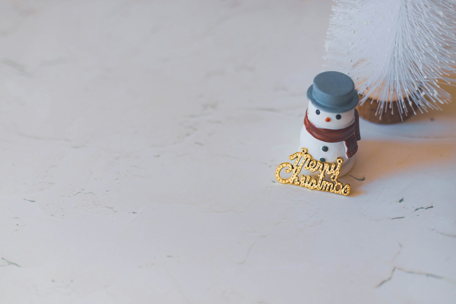 一个戴蓝色帽子和围巾的雪人旁边有金色圣诞装饰
