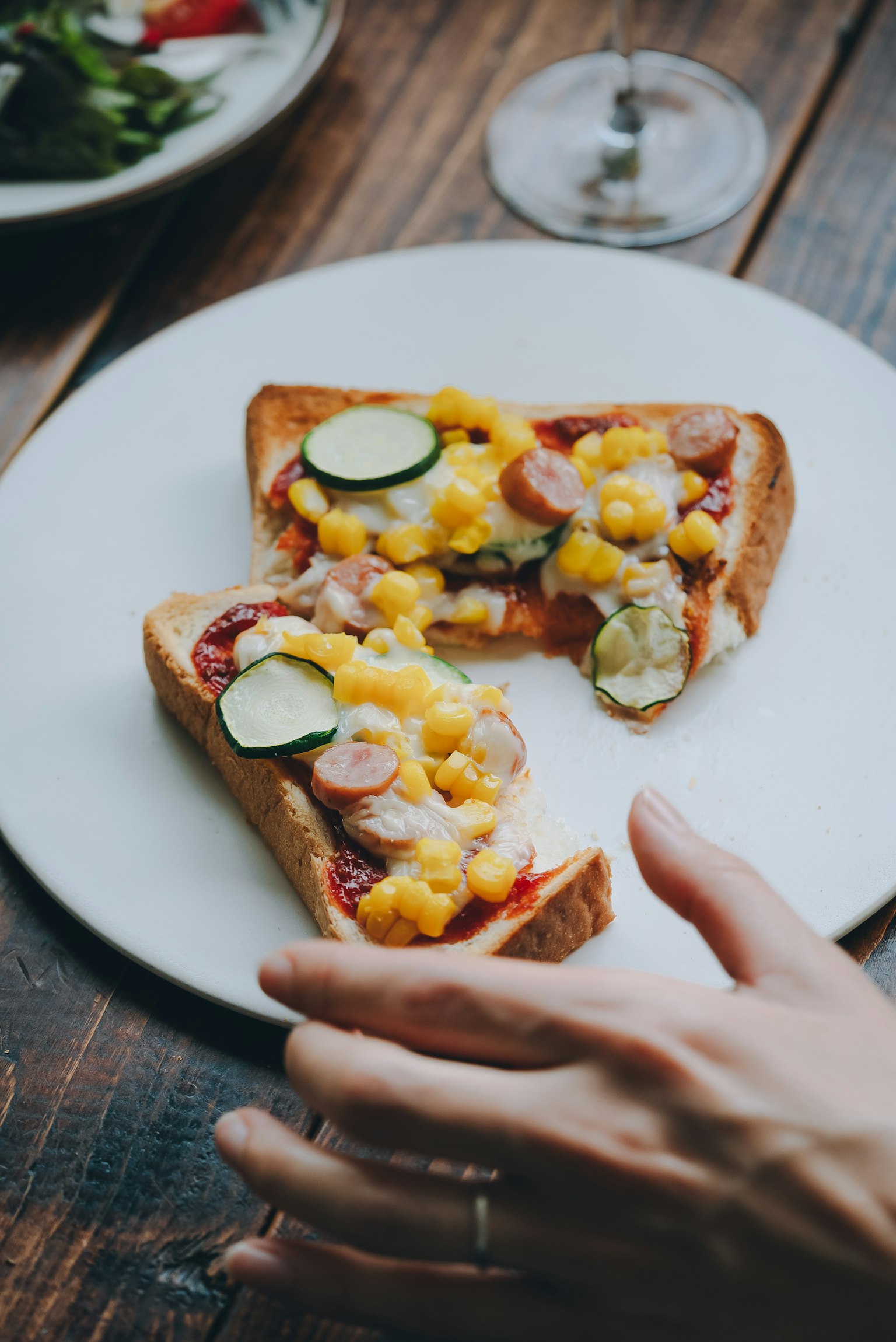 Roti bakar keju dan sayuran disajikan di piring putih dengan tangan