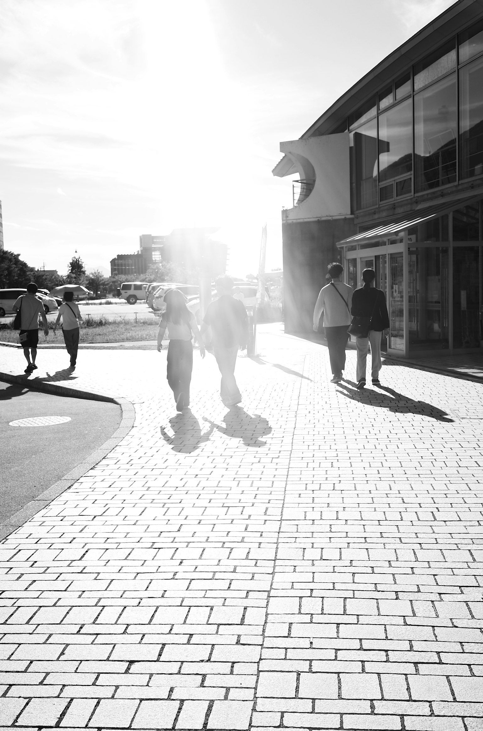 Silhouettes de personnes marchant sous un soleil éclatant sur un trottoir de la ville