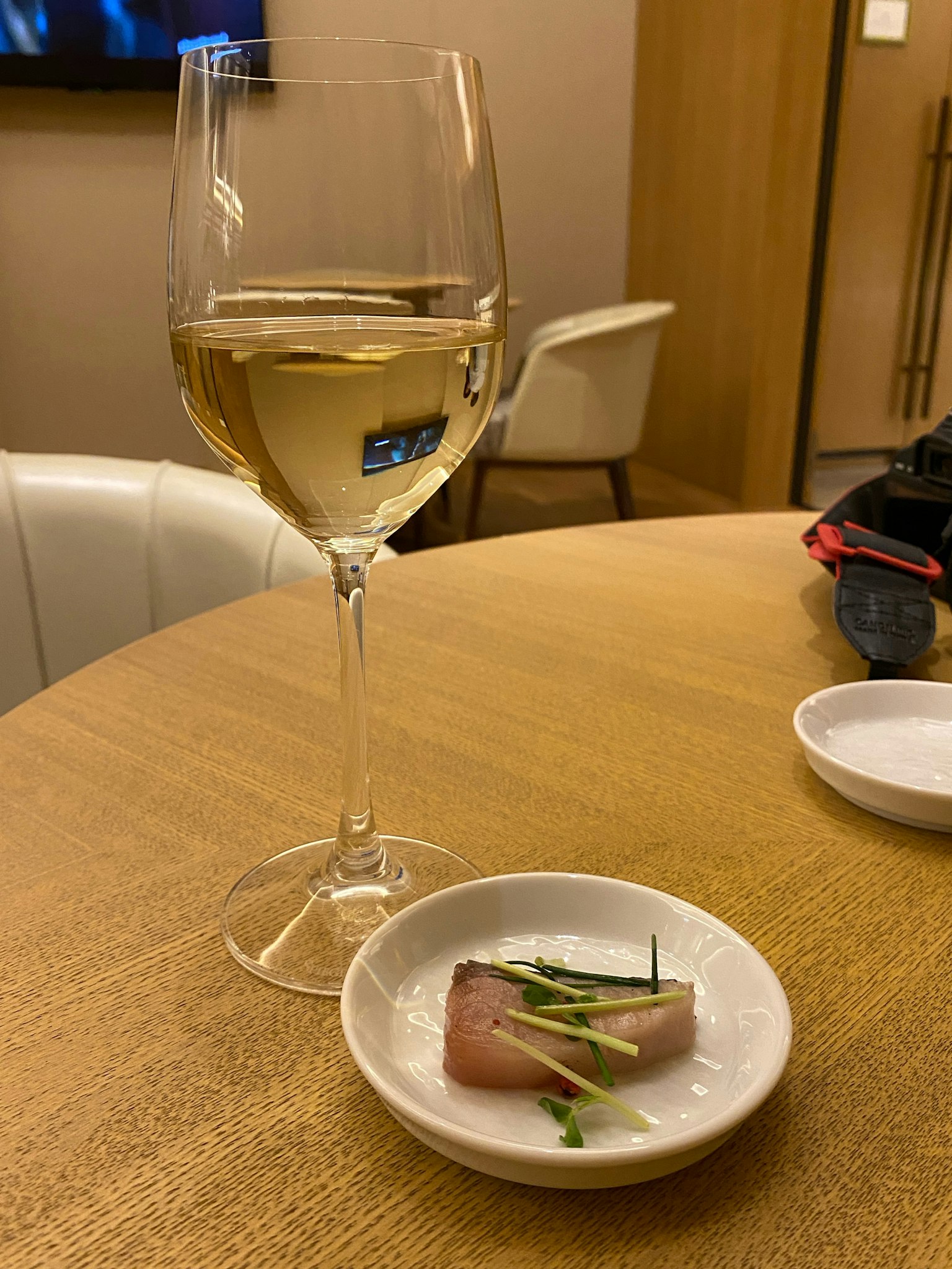 Bild eines Glases Weißwein und Sashimi auf einem kleinen Teller