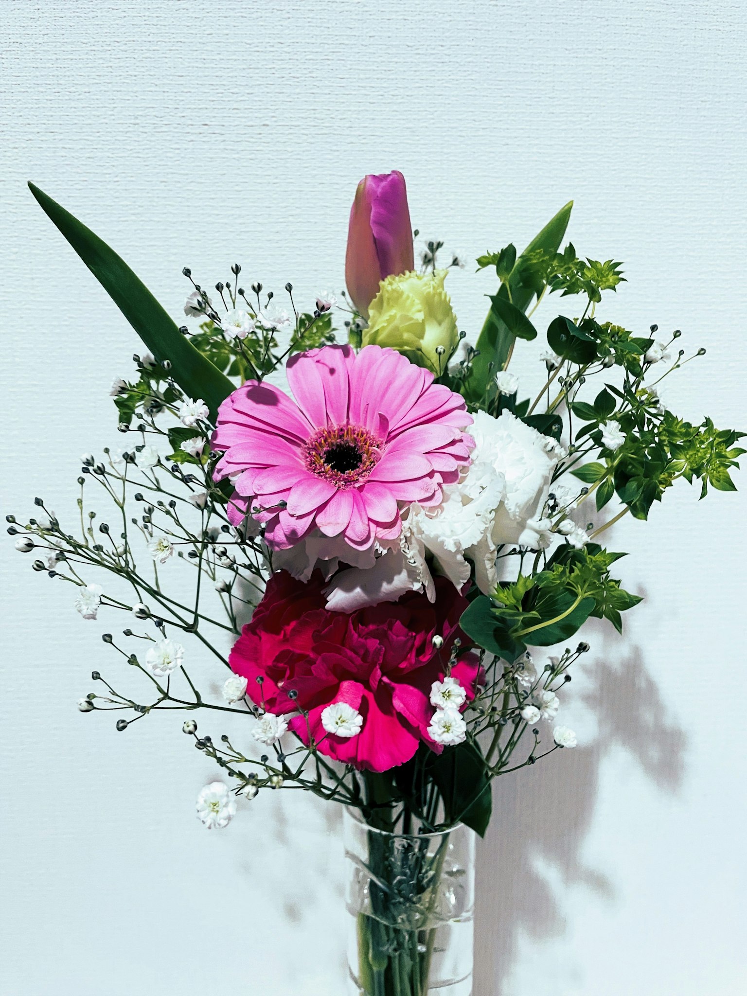 Ramo con margaritas rosas y flores blancas con follaje y pequeñas flores