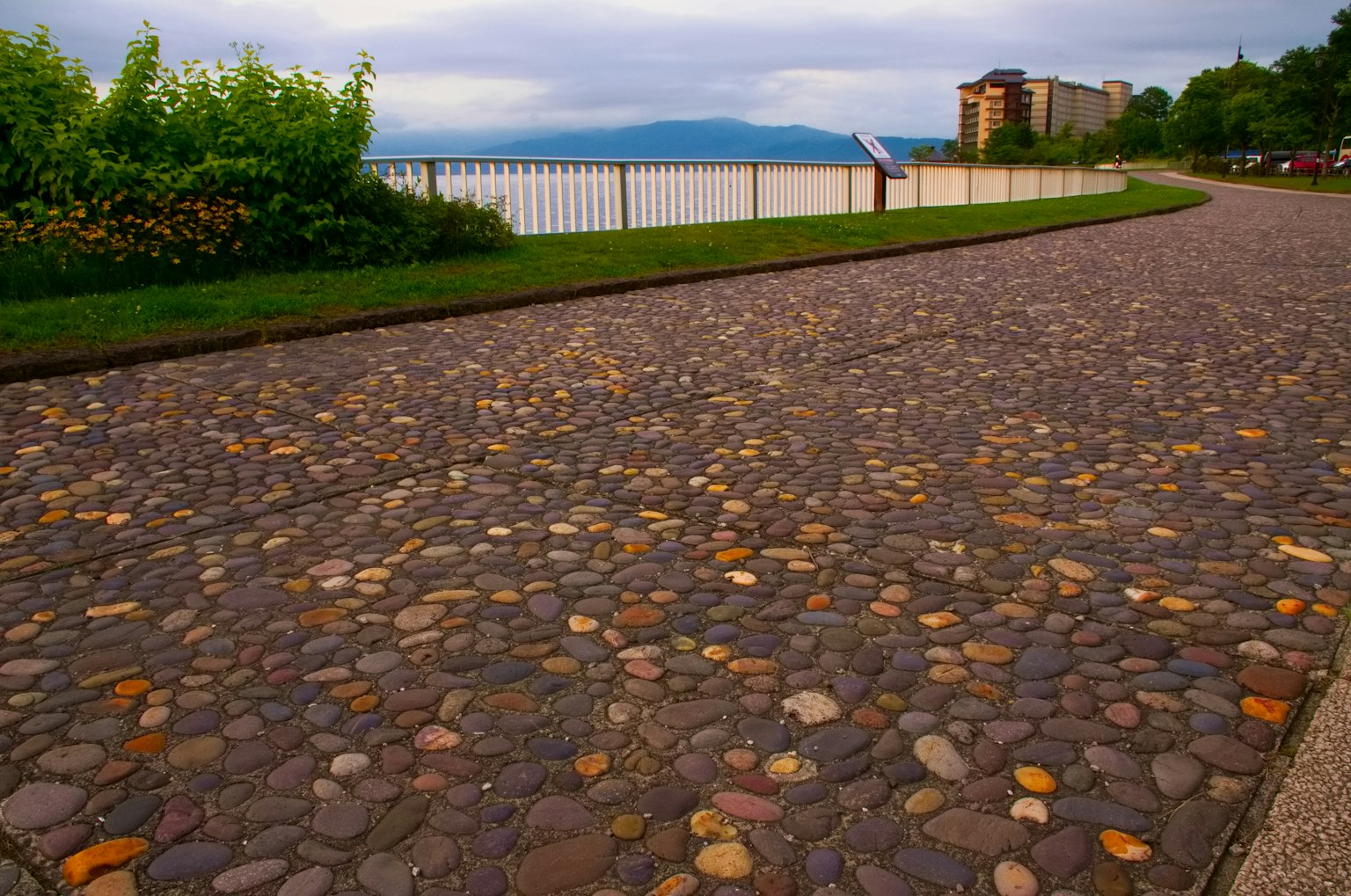 Chemin en pavés avec de la verdure et vue sur l'eau