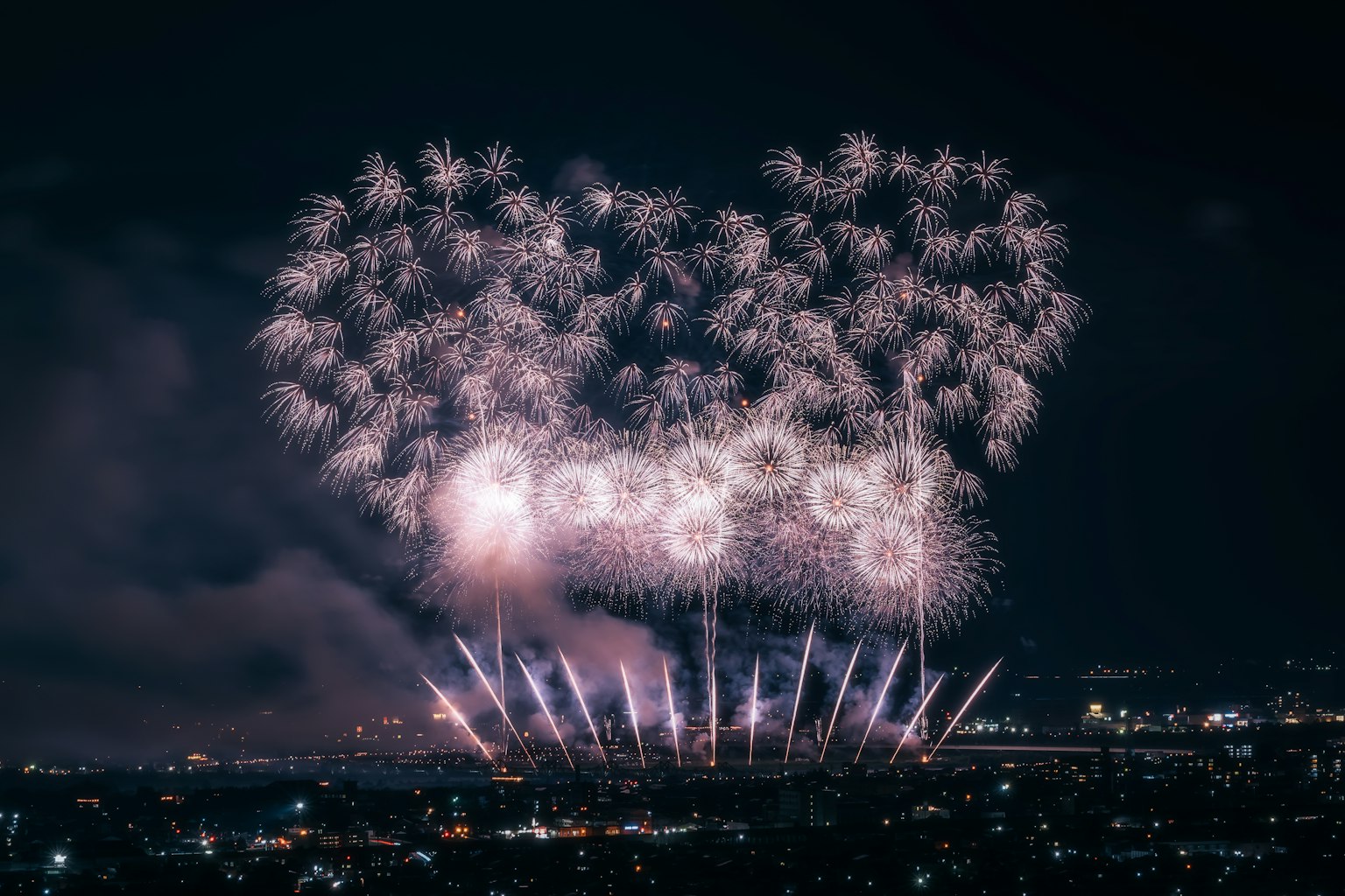 Bellissimo spettacolo di fuochi d'artificio nel cielo notturno con colori bianco e rosa