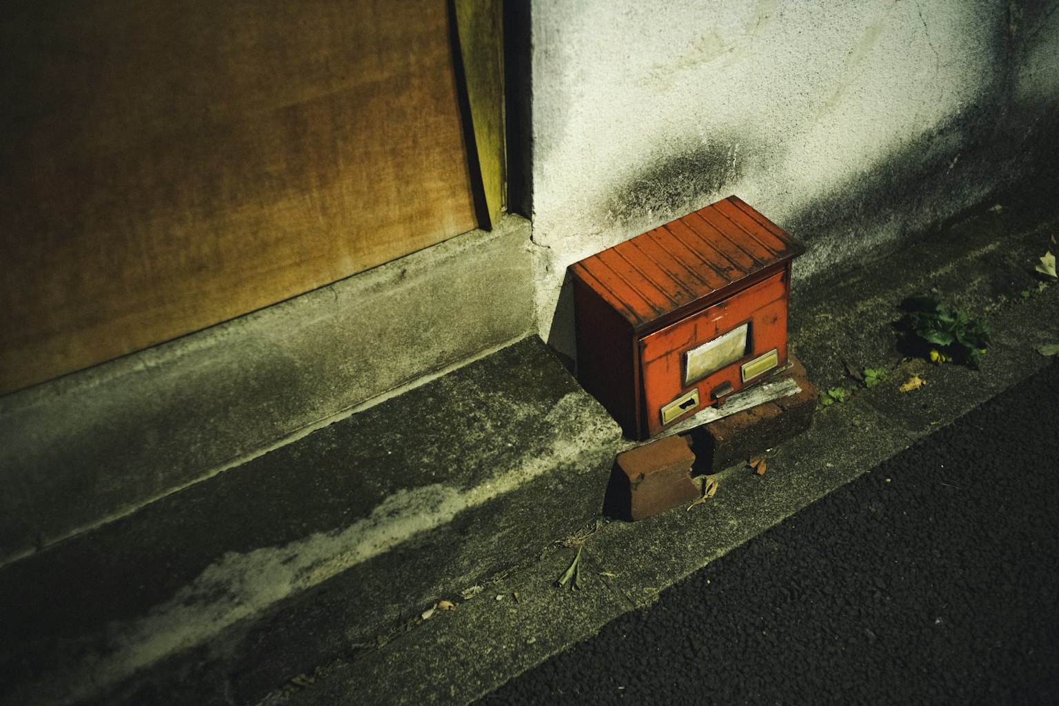 赤い郵便箱が壁のそばに置かれている