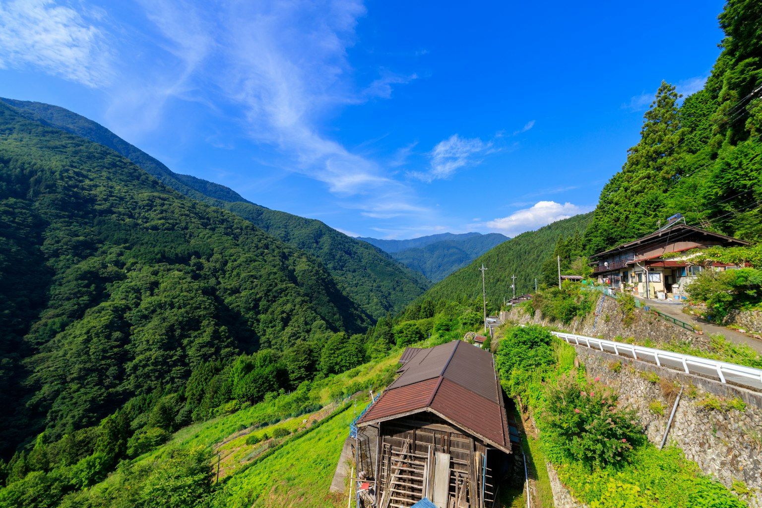 Ancien bâtiment en bois entouré de montagnes verdoyantes et d'un ciel bleu