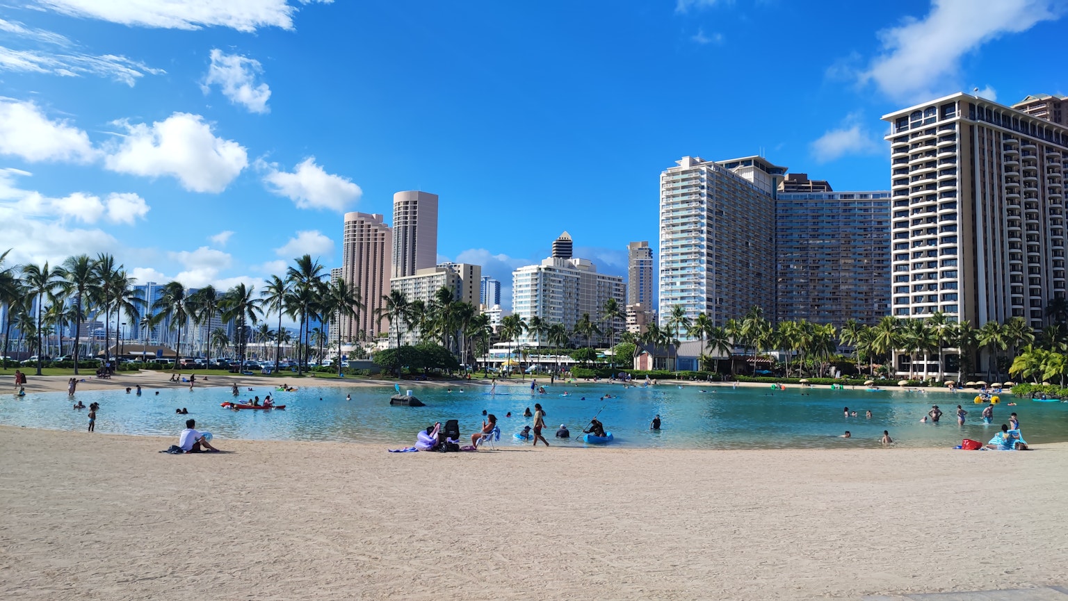 Cảnh quan tuyệt đẹp của mọi người tận hưởng bãi biển ở Hawaii với các tòa nhà cao tầng dưới bầu trời xanh